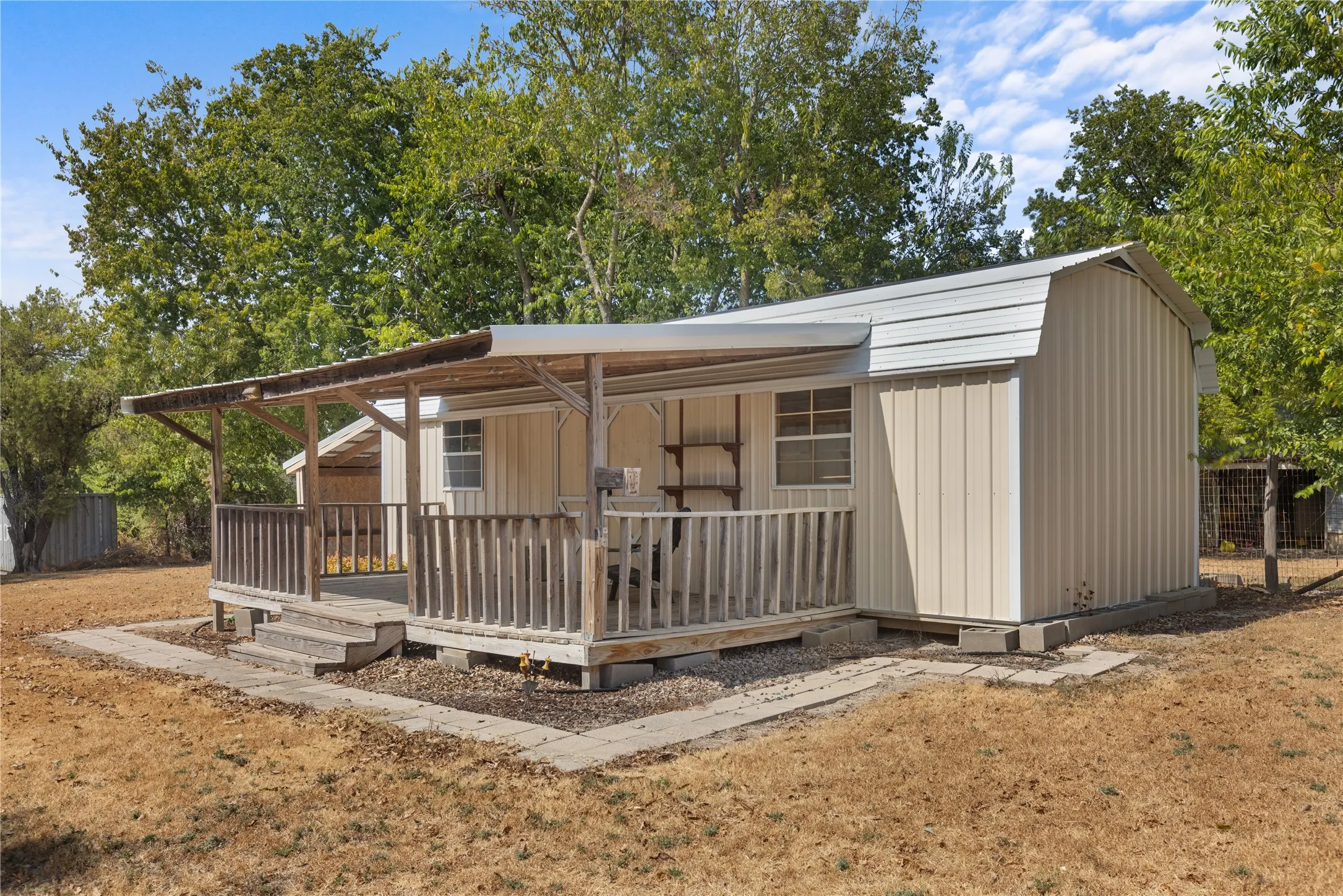 Front porch with wooden railings and steps, featuring a metal roof extension