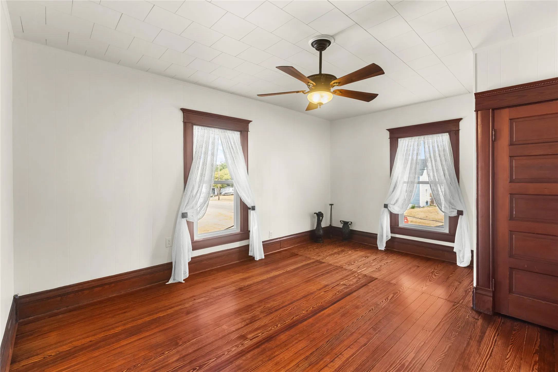 Wood-finish flooring, white walls, and a ceiling fan with integrated lighting