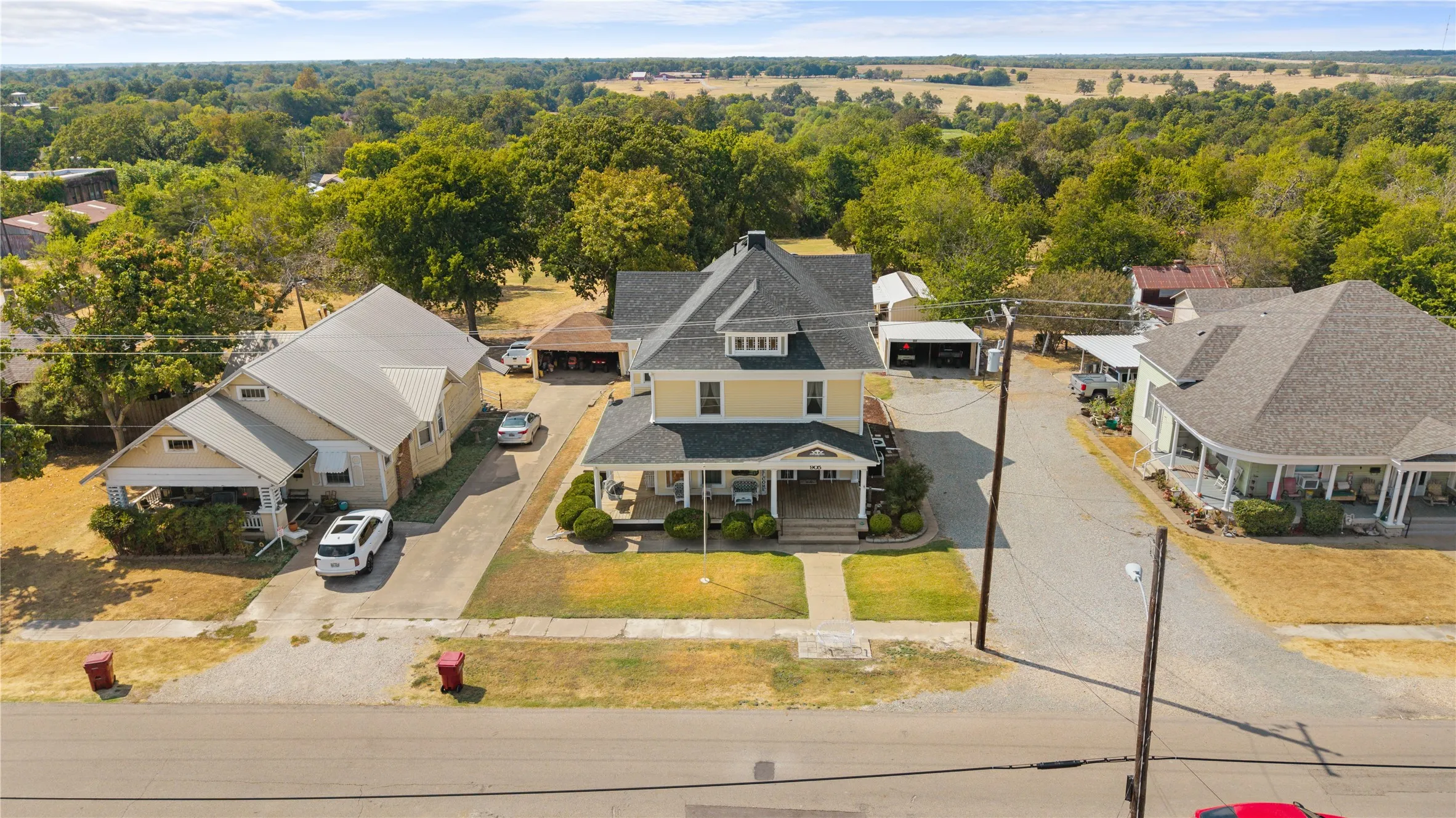 Two-story home with a prominent gabled roof and covered front porch, featuring an extended paved driveway