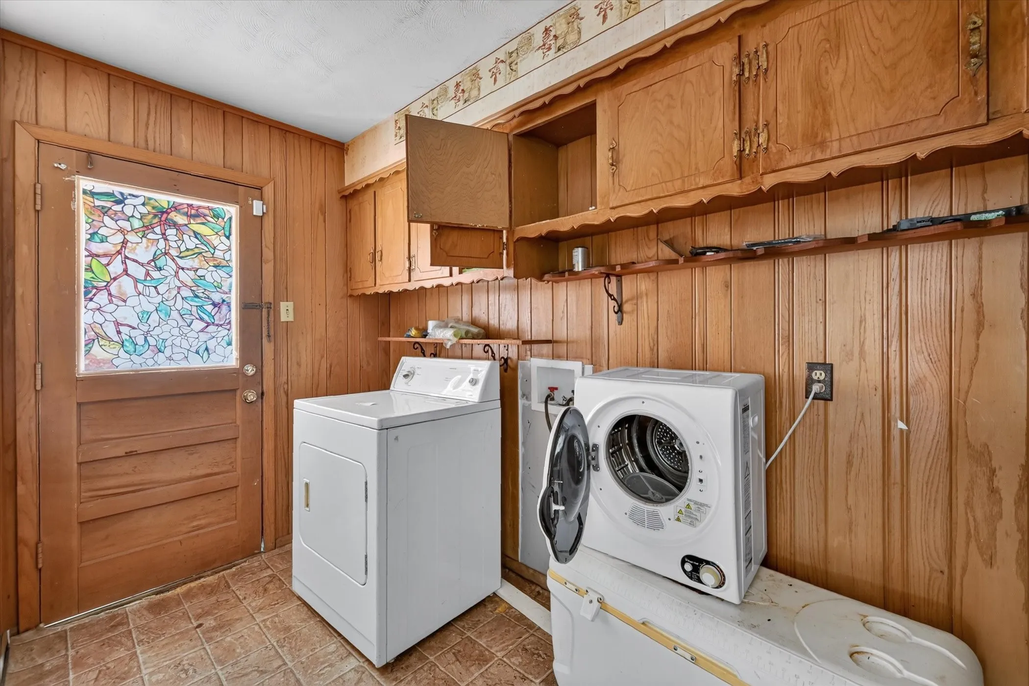 Wood-paneled room featuring built-in cabinetry, upper shelving, and a patterned glass door
