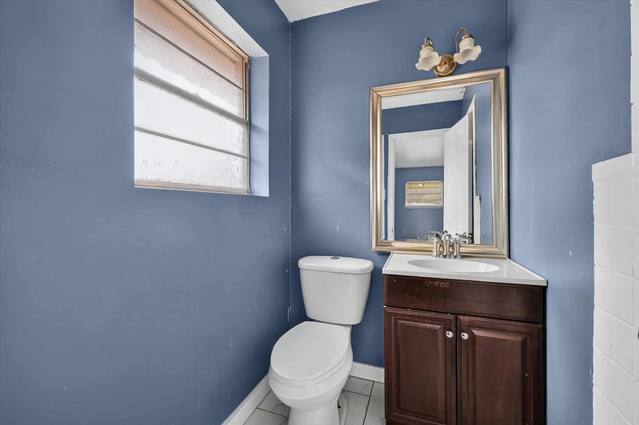 Compact bathroom featuring a corner vanity with a white countertop, coordinating sink, and chrome-finish faucet