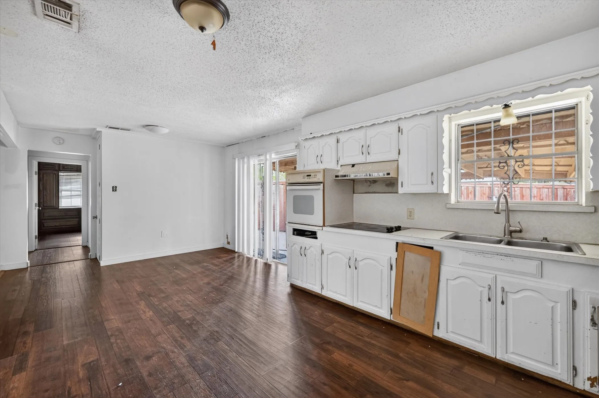 Kitchen featuring white cabinetry, built-in oven, stainless steel sink, and wood-finish flooring