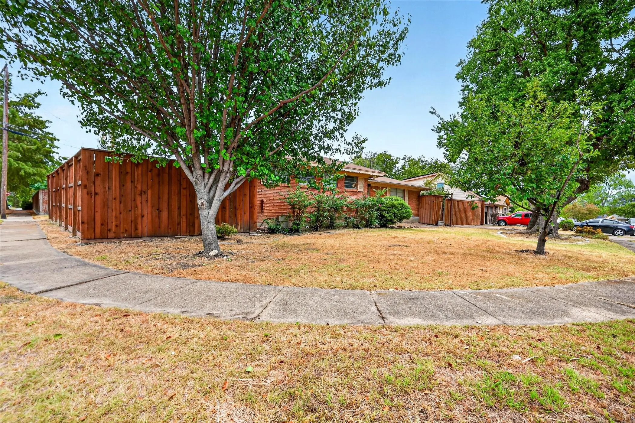 Brick exterior residence with mature trees and a private wood fence