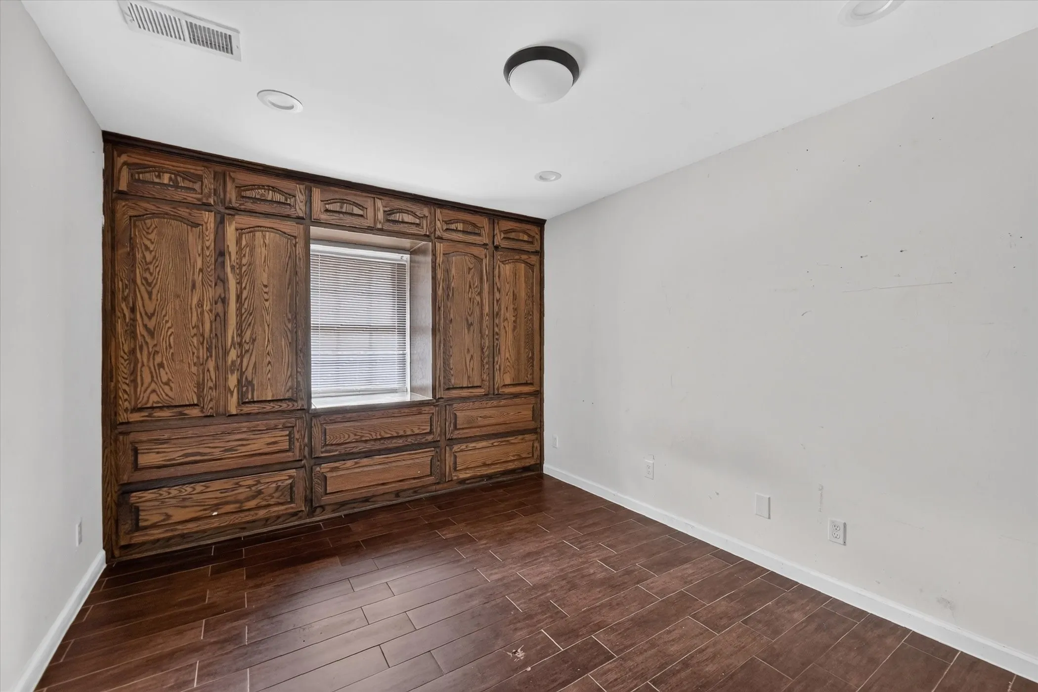 Built-in wood cabinetry with a window, recessed lighting, and wood-finish flooring