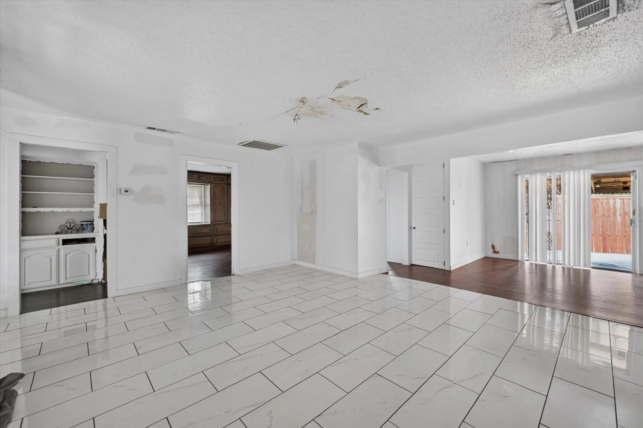 White tile flooring, sliding glass patio door, built-in shelving, white cabinetry, dark wood-finish flooring
