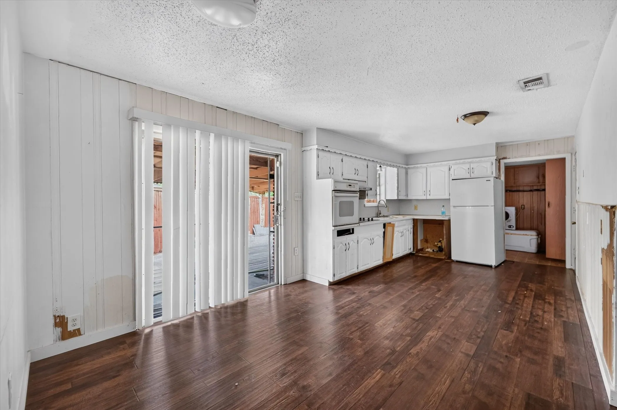Wood-finish flooring throughout, white cabinetry, integrated wall oven, and sliding glass door