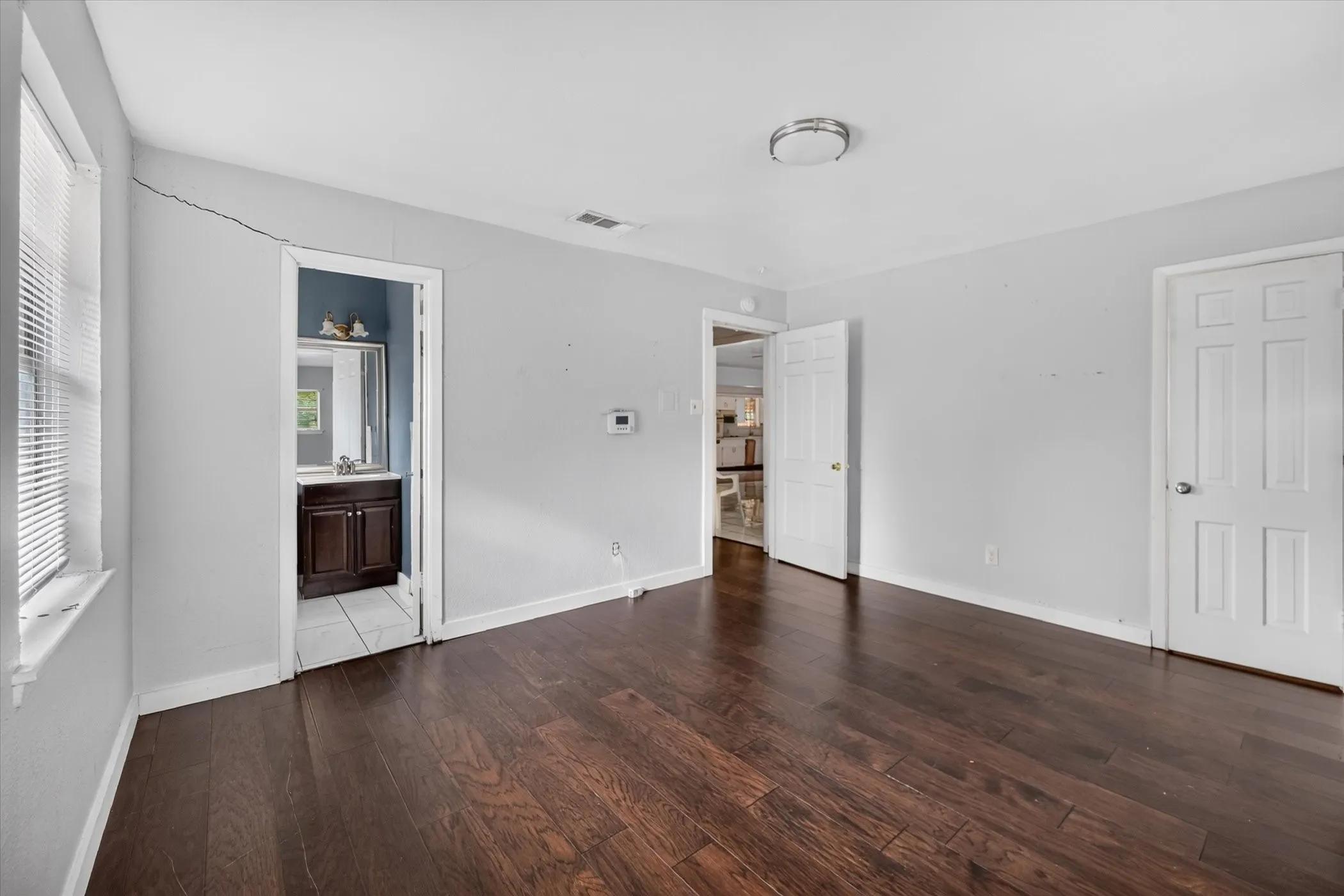 Wood-finish flooring throughout, white interior doors, and a flush mount ceiling light fixture