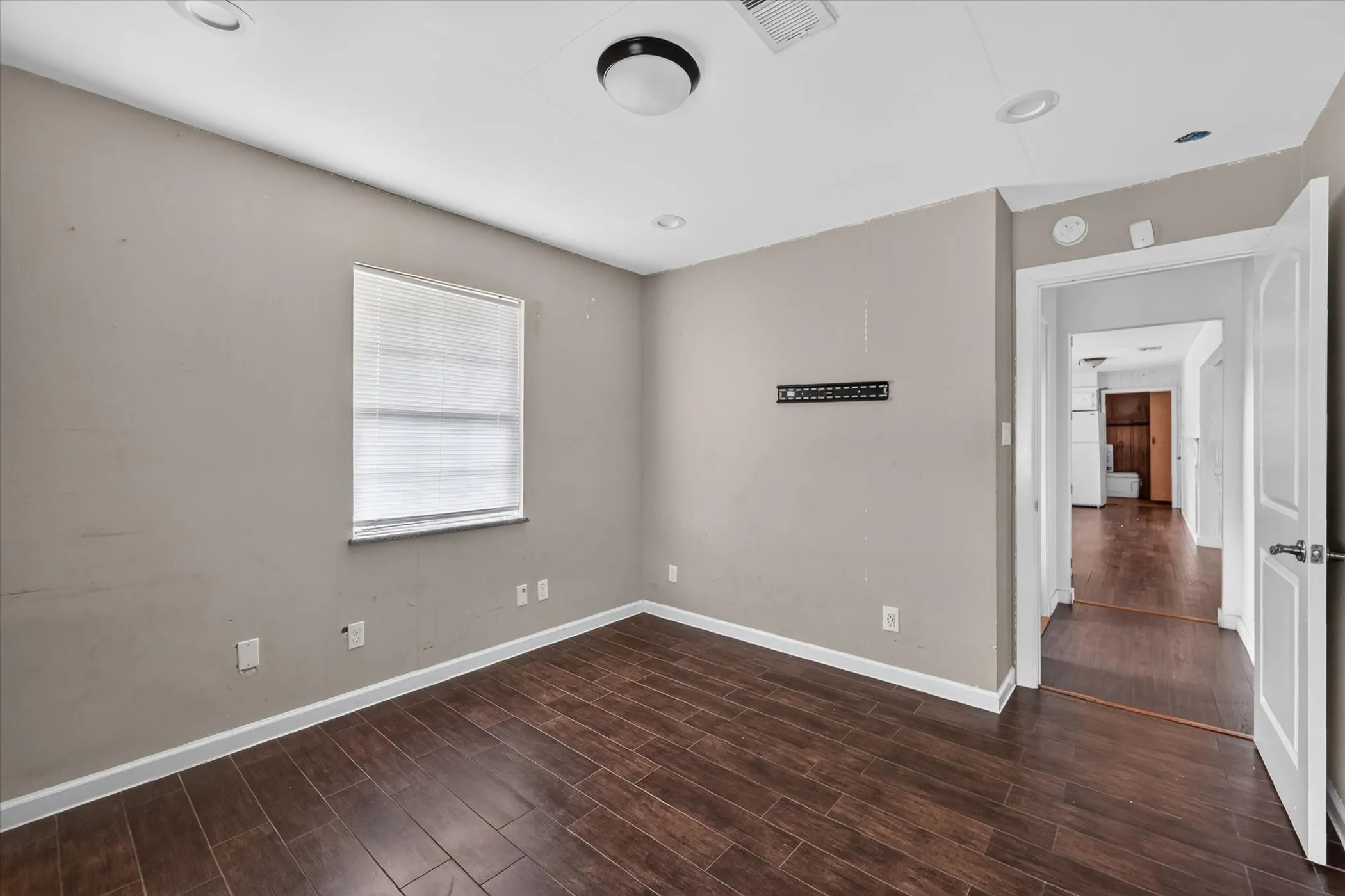 Wood-finish flooring with white trim and a neutral wall color