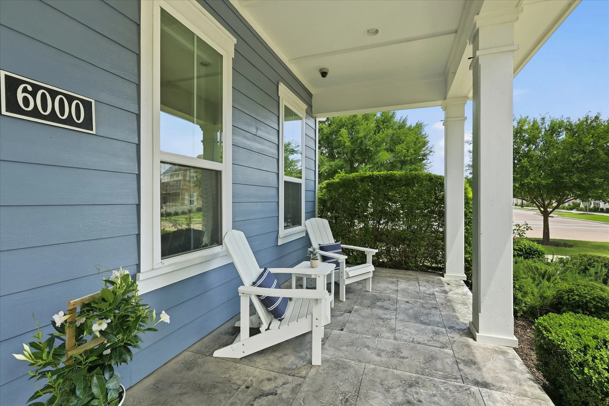 Covered front porch featuring, white architectural columns, and a light blue siding exterior