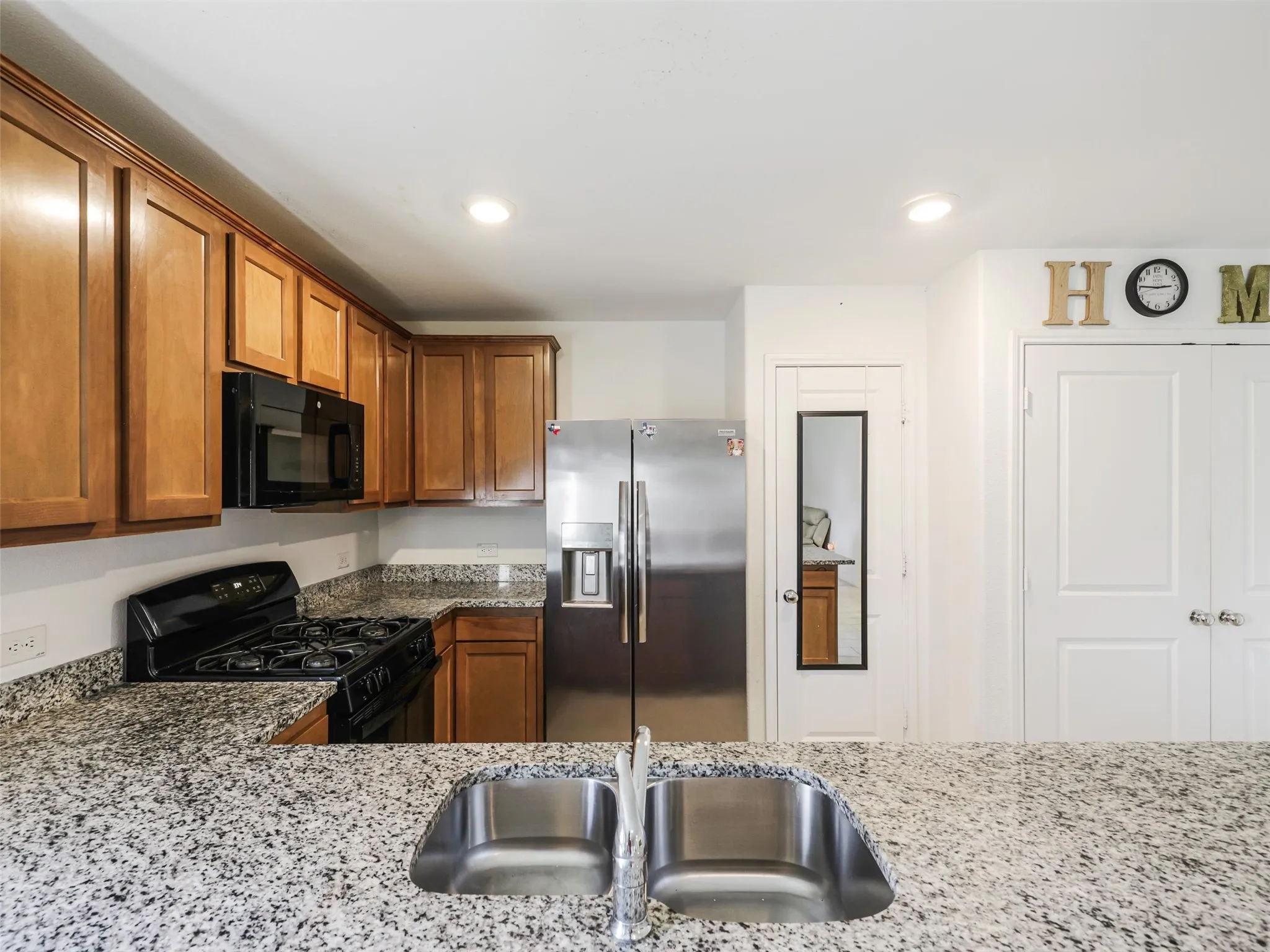 Kitchen featuring a double basin stainless steel sink, light-toned cabinetry, and granite-style countertops