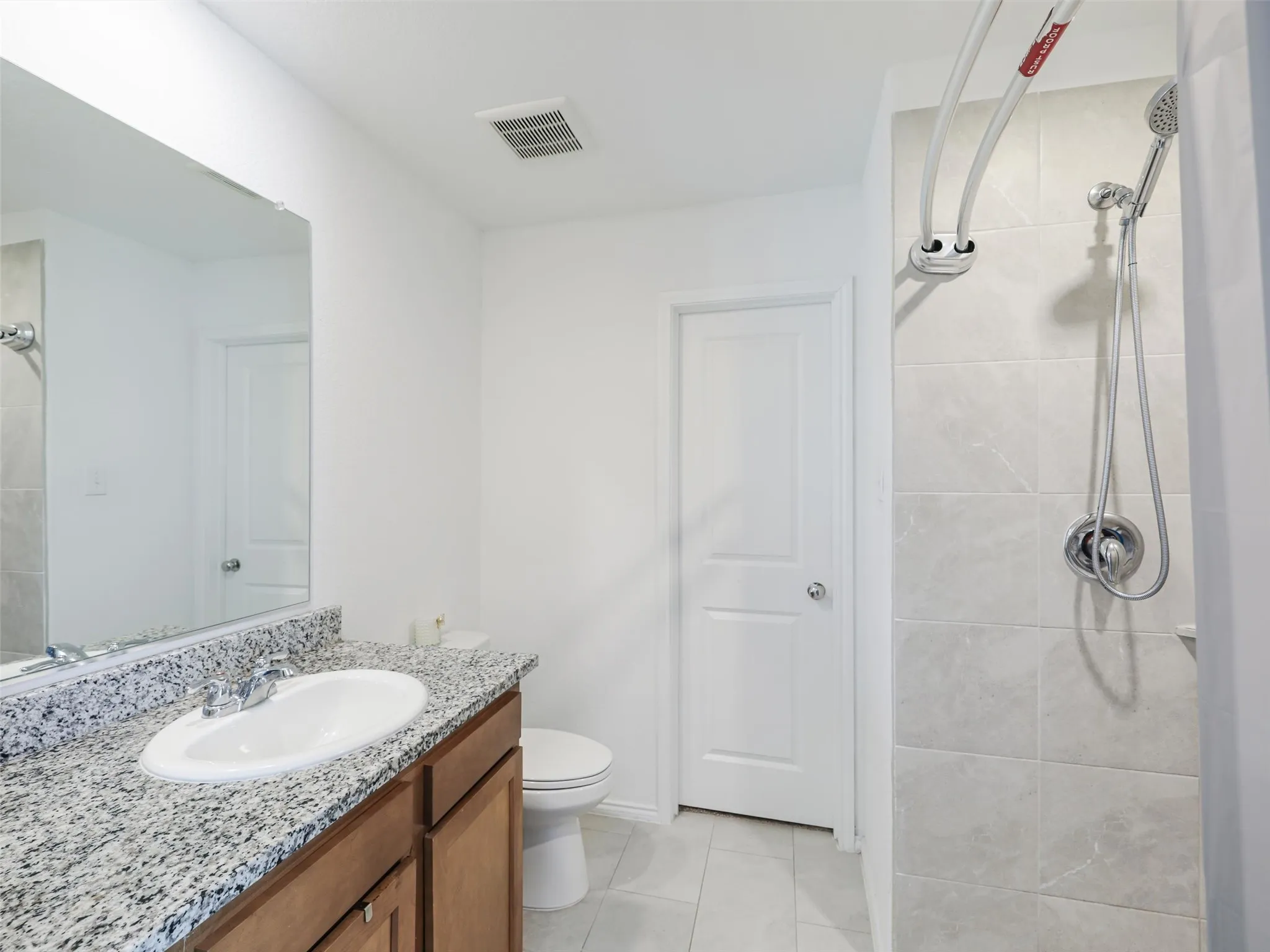 Bathroom featuring a single vanity with stone-finish countertop, undermount sink, and wood-finish cabinetry
