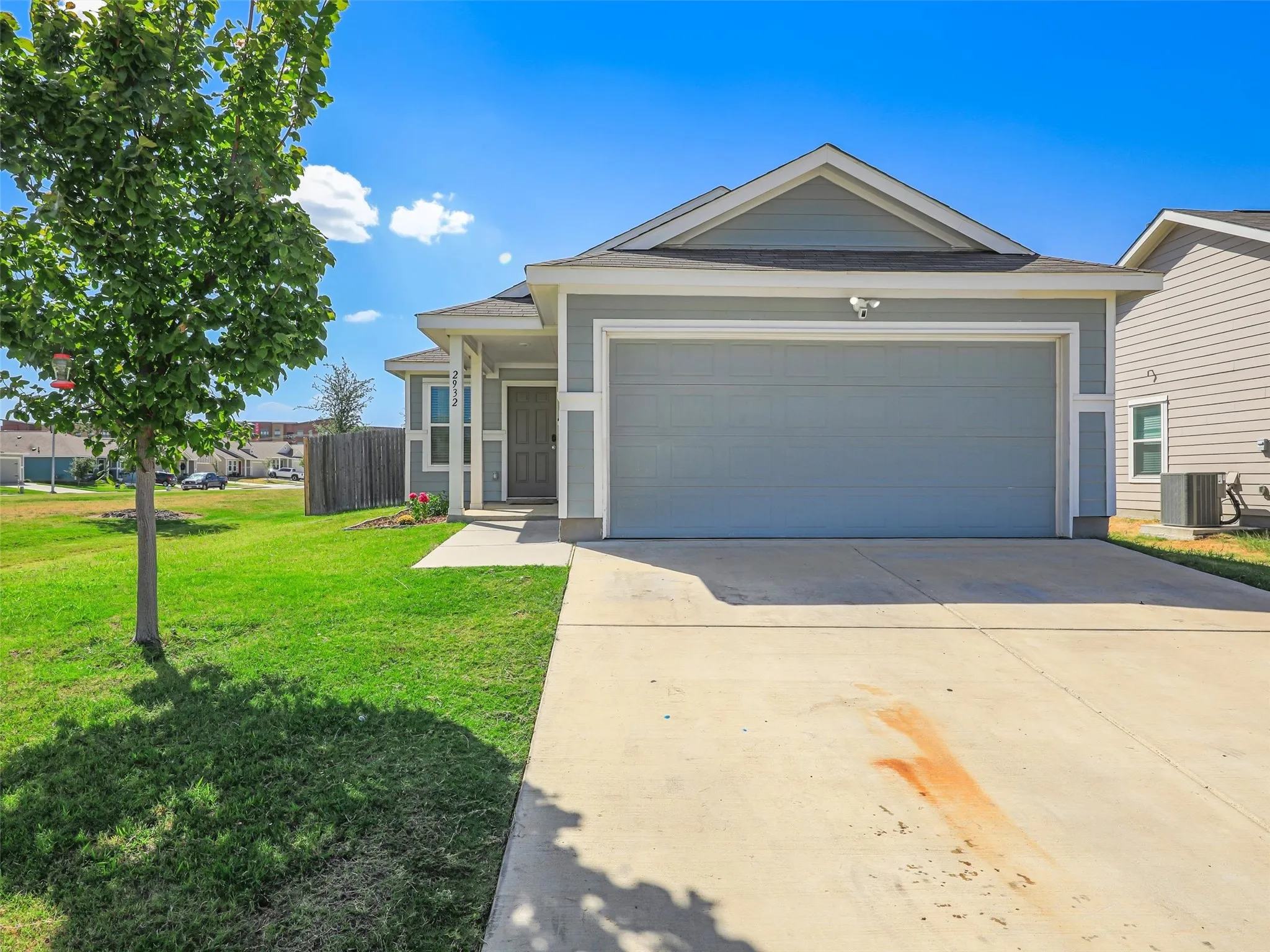 Single-story residence featuring light gray siding, an attached garage, and a concrete driveway
