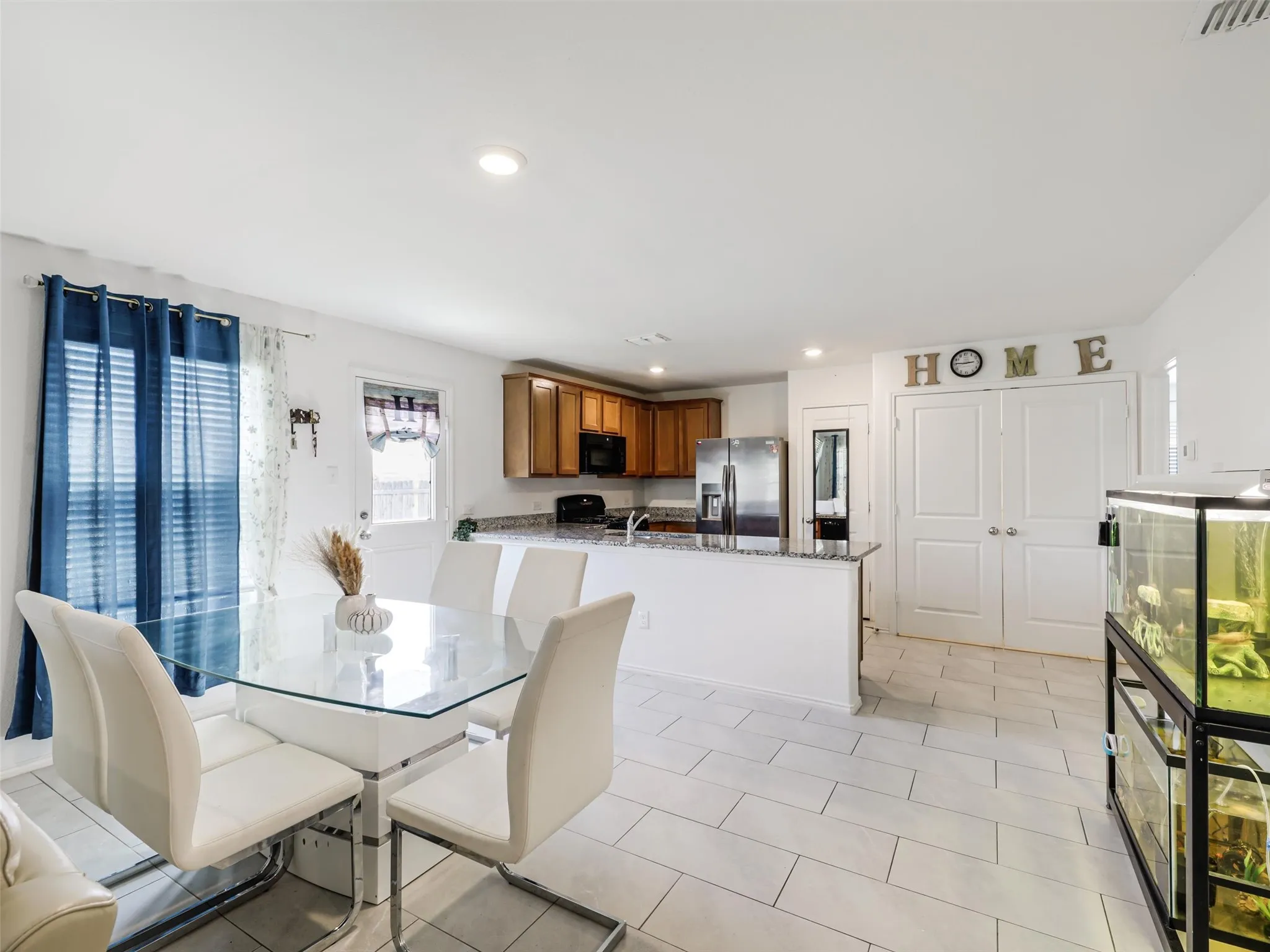 Open-concept dining and kitchen area with light-toned rectangular floor tiling