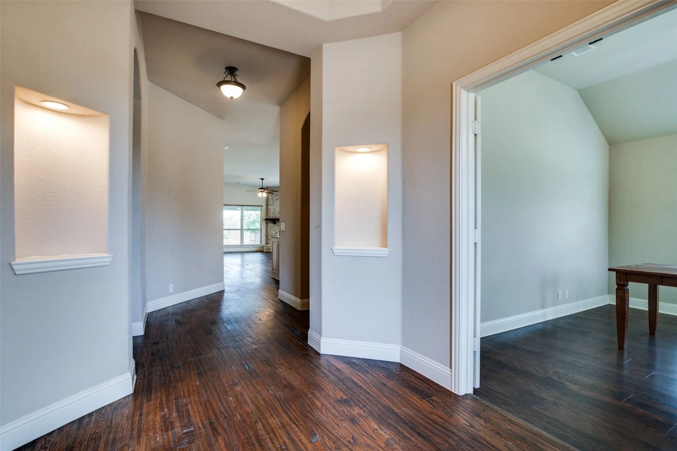 Wood-finish flooring throughout, arched hallways, recessed display niches with lighting, and a tray ceiling