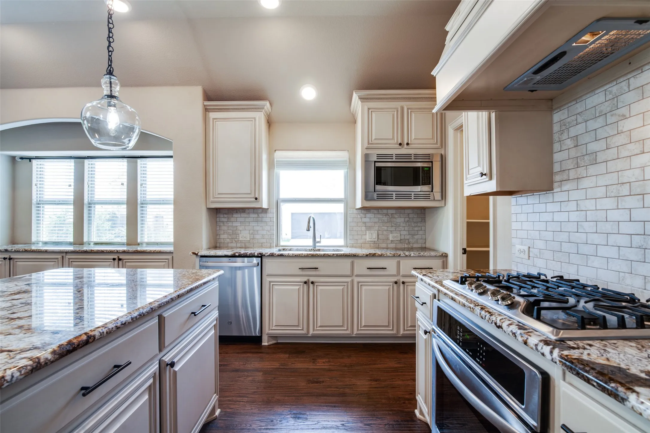 Kitchen featuring granite countertops, wood-finish flooring, white subway tile backsplash, recessed lighting, and stainless steel appliances