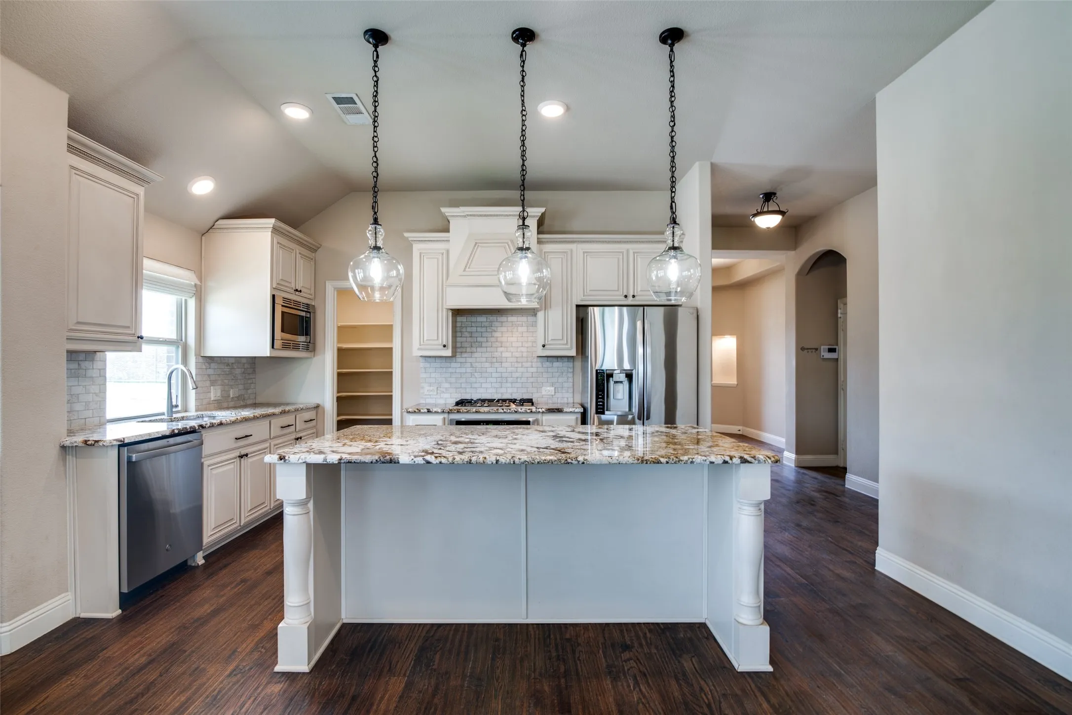 Kitchen featuring a central island with a granite countertop, white cabinetry, a built-in stainless steel microwave, and wood-finish flooring