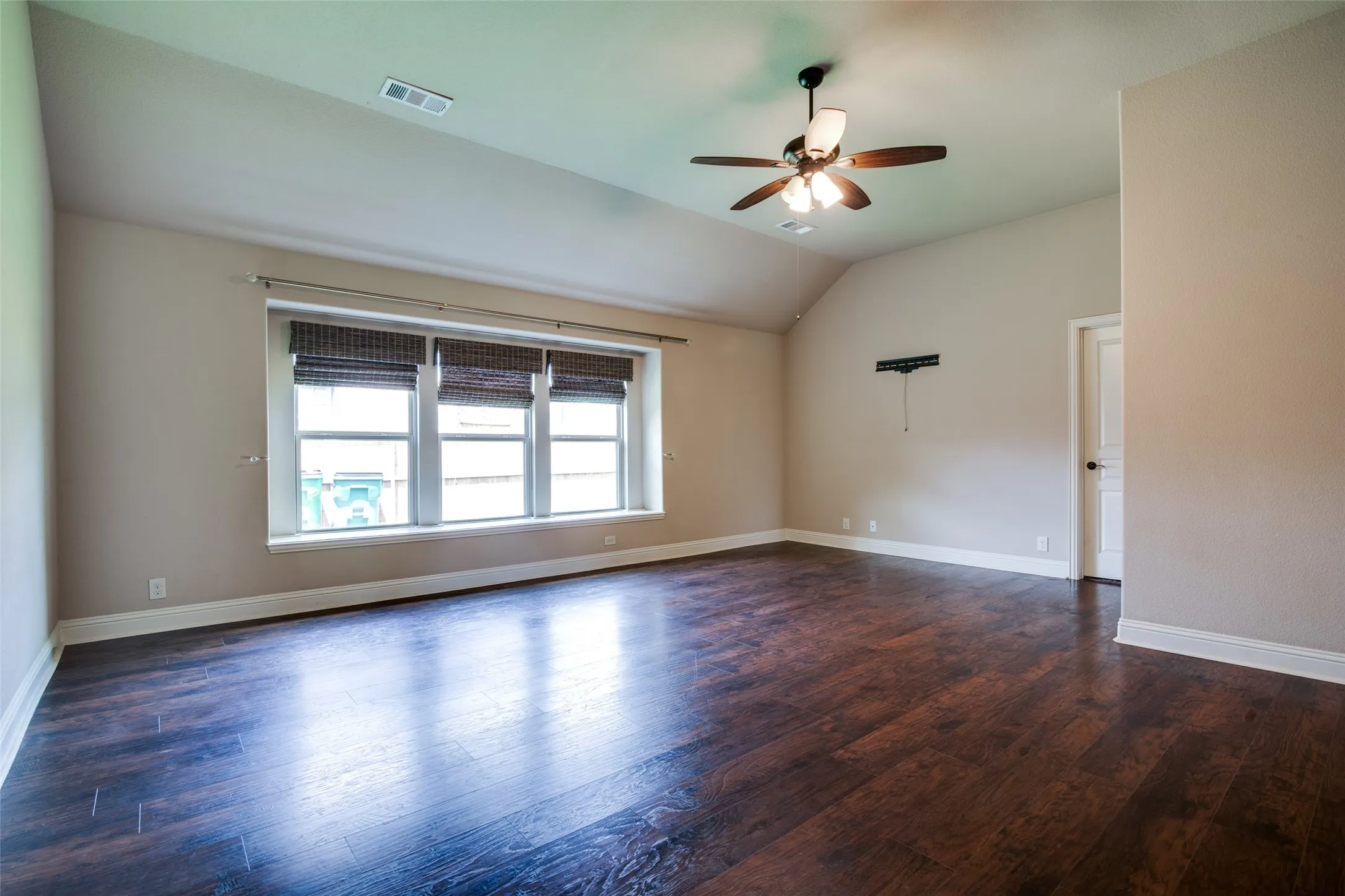 Vaulted ceiling with a ceiling fan, wood-finish flooring, and multiple windows with blinds