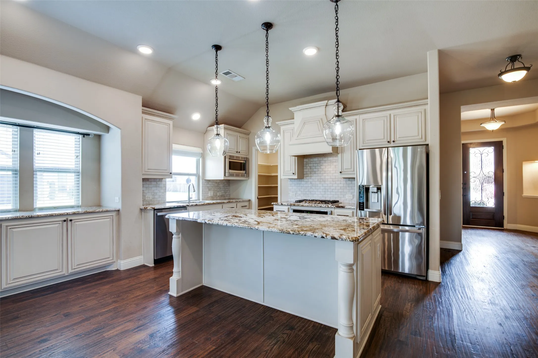Wood-finish flooring, recessed lighting, white cabinetry, granite countertops, and stainless steel appliances