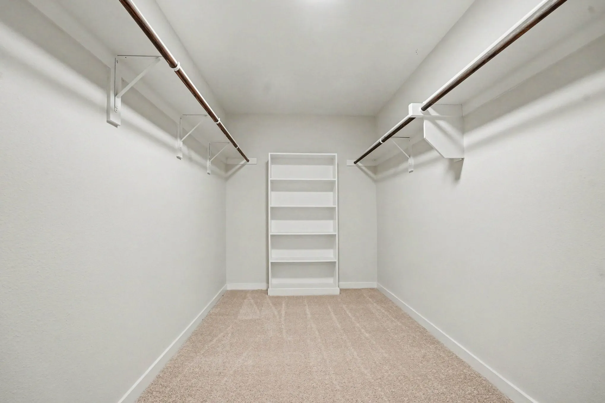 Master- Neutral-toned carpeting, built-in shelving unit, and dual clothing rods