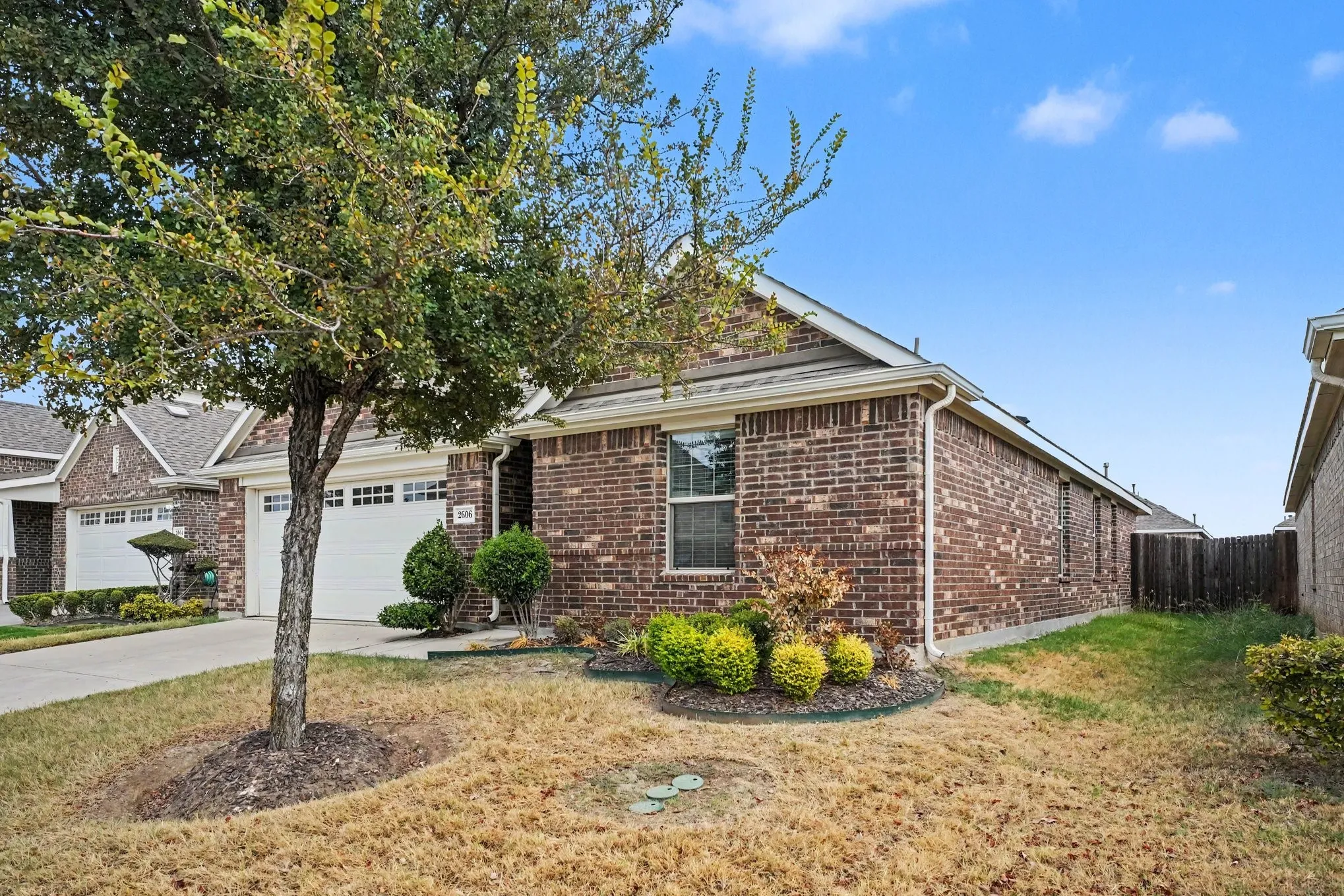 Brick exterior with white garage doors and a paved driveway