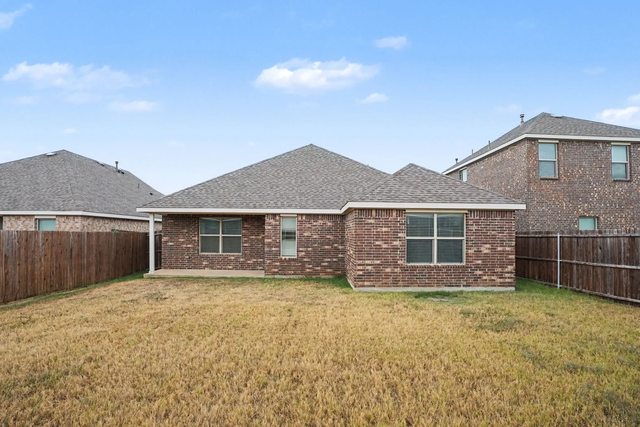 Brick exterior with multiple windows and a covered patio