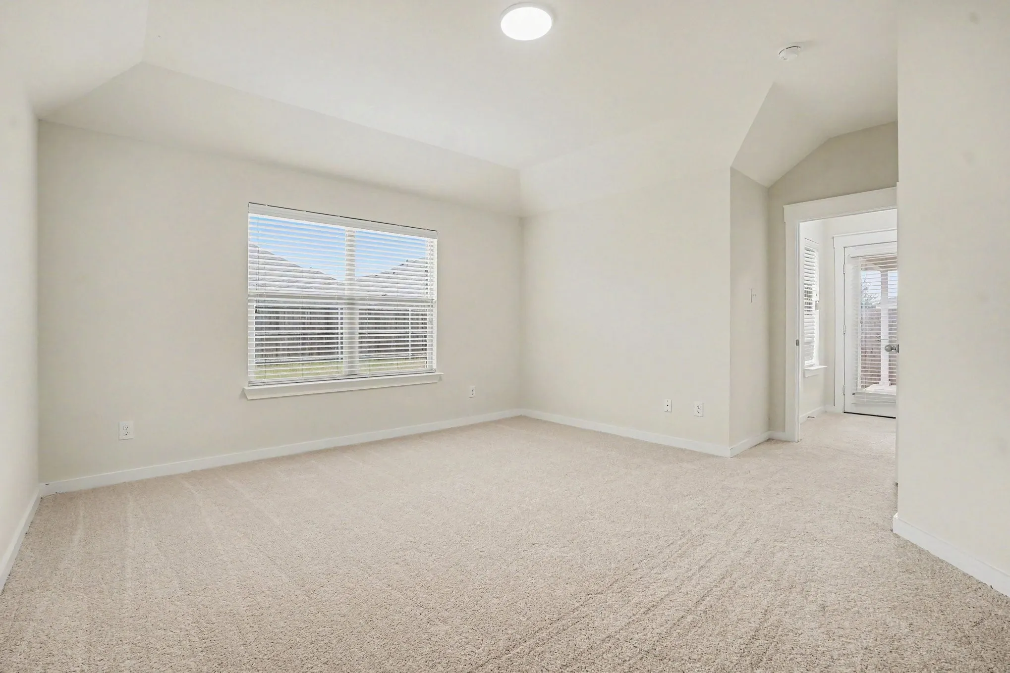Carpeted room featuring a window with blinds, vaulted ceiling, and recessed lighting