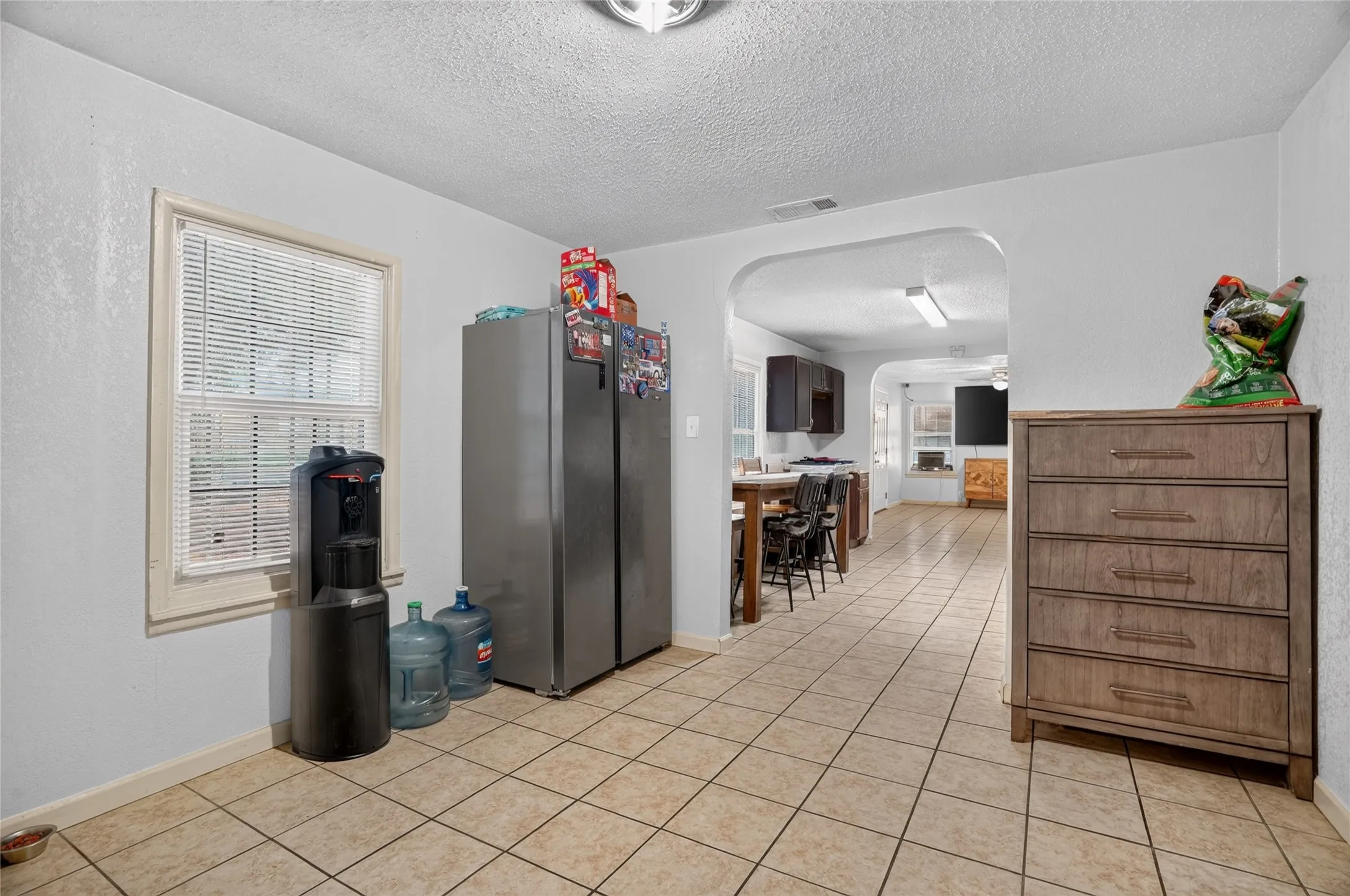 Arched doorway entry, tiled flooring, window with blinds, recessed lighting, wood-finish cabinetry
