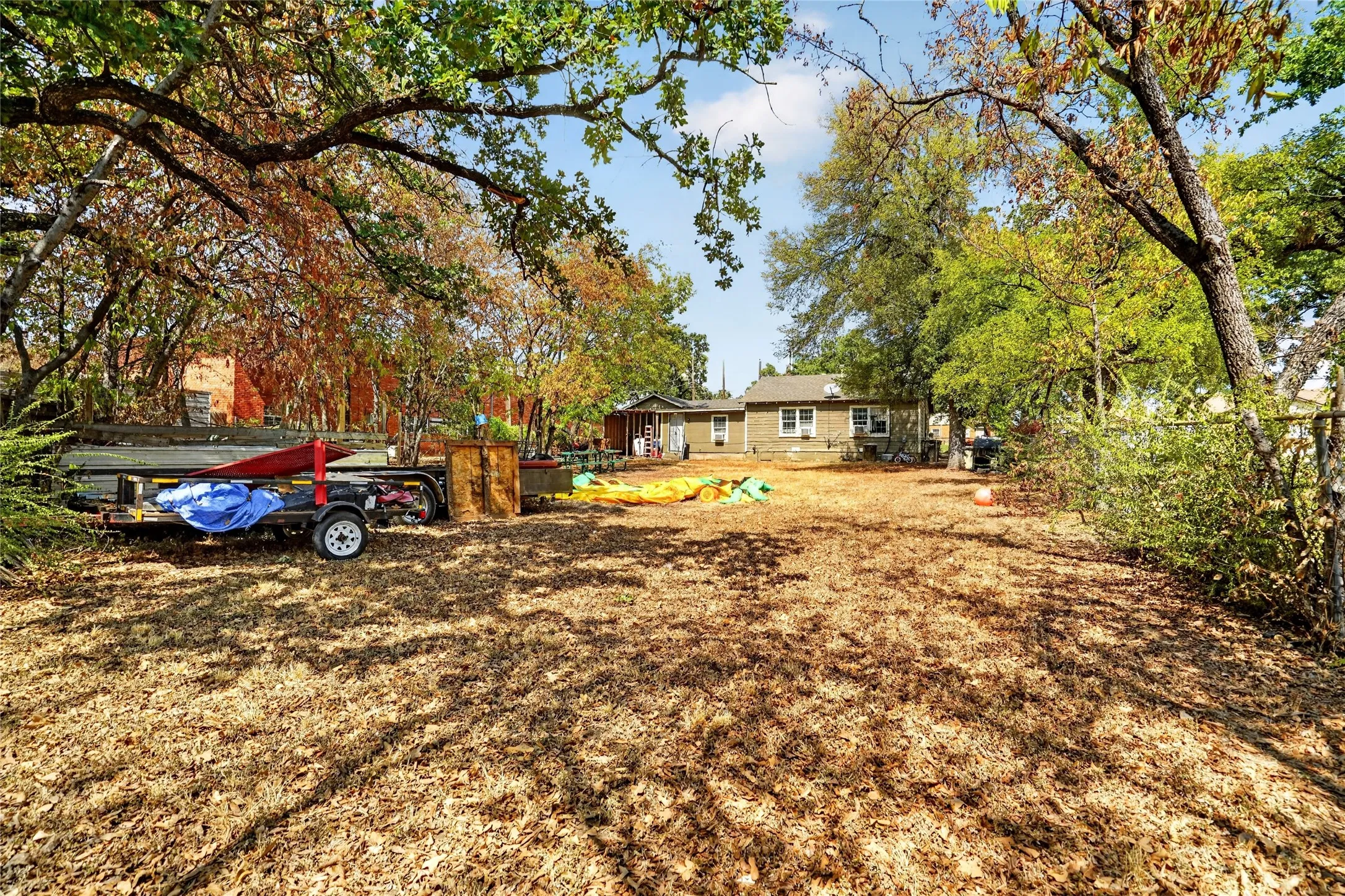 Expansive outdoor space featuring mature trees and a residential structure