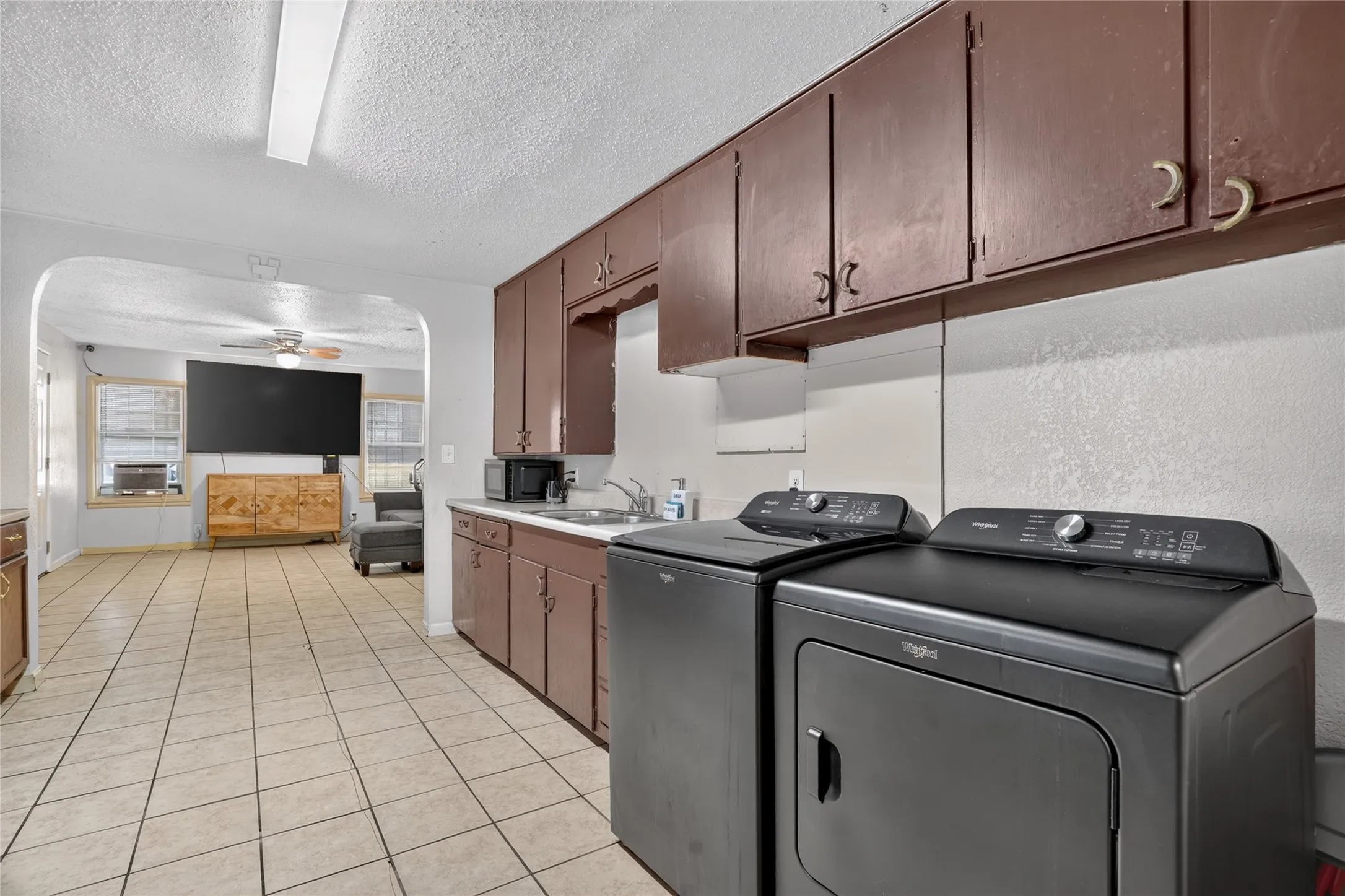 Tile flooring, built-in cabinetry, arched entryway, and a ceiling fan