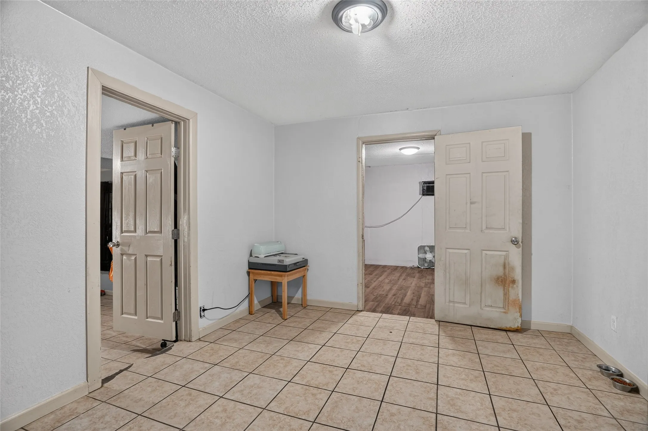 Tiled flooring with neutral tones, white painted walls, and a flush-mount ceiling light fixture