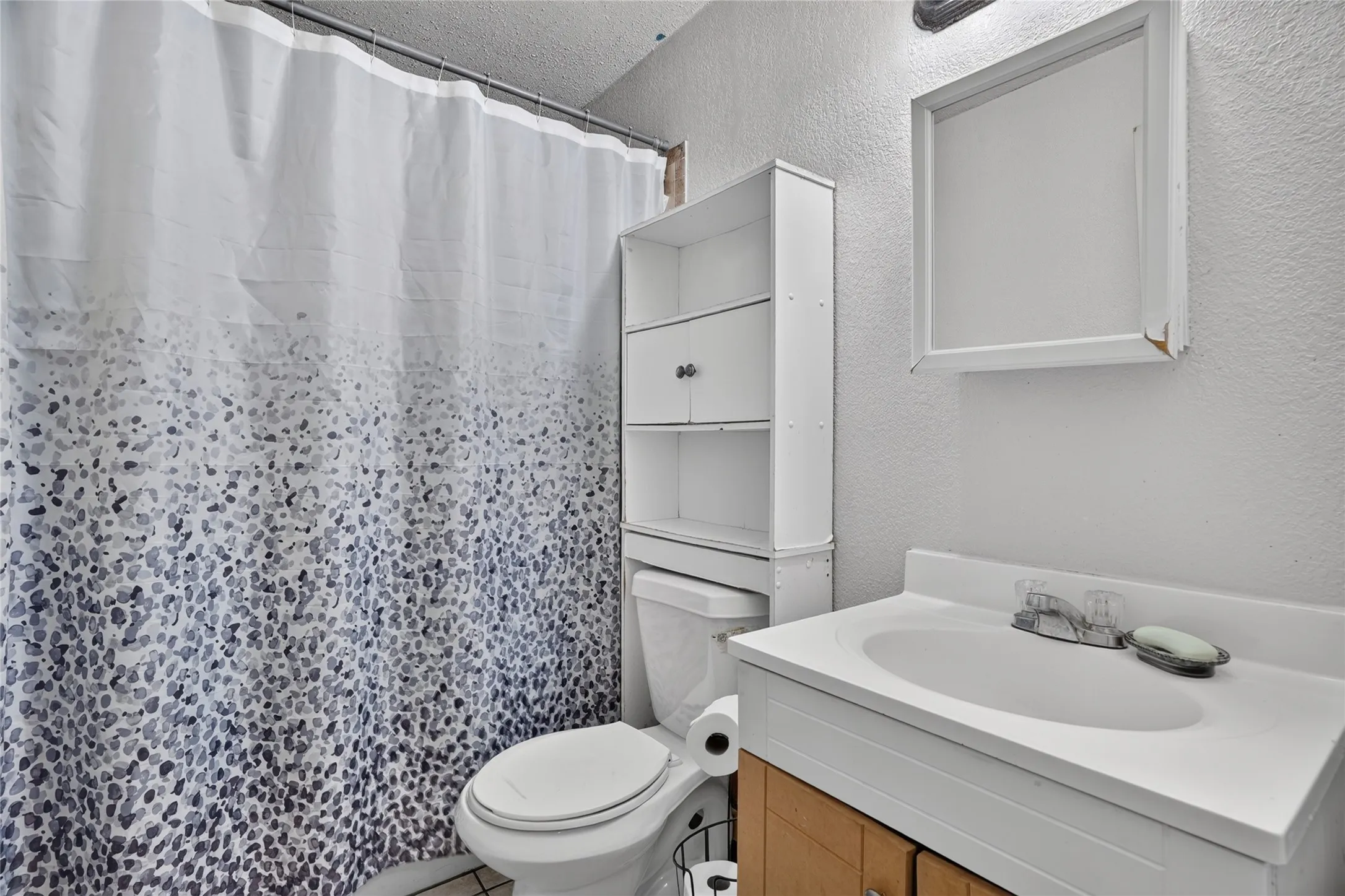 White vanity with integrated sink and chrome-finish faucet, framed mirror, and built-in white storage shelving