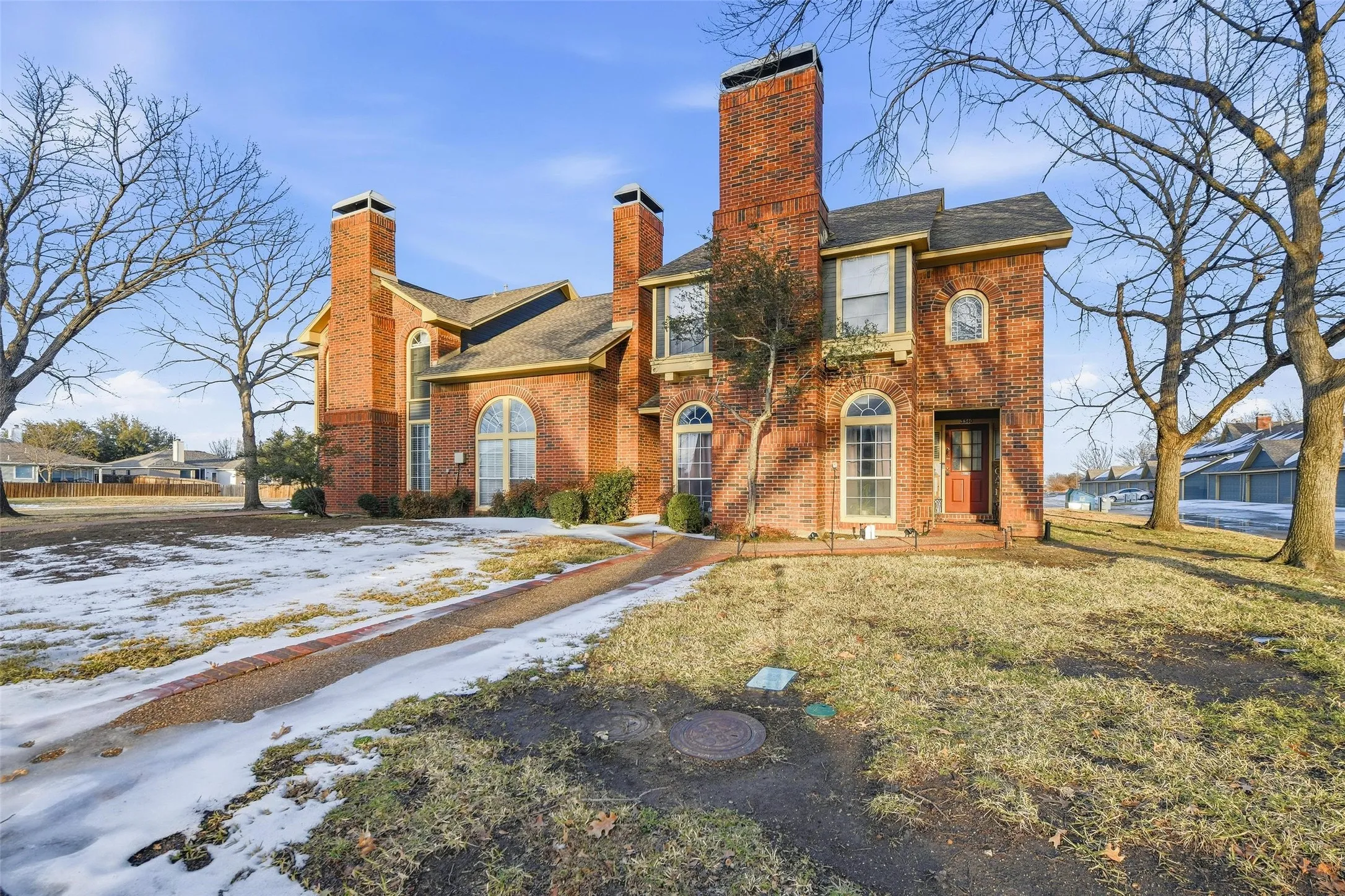 Brick exterior with multiple prominent chimneys, arched windows, and an arched entry door