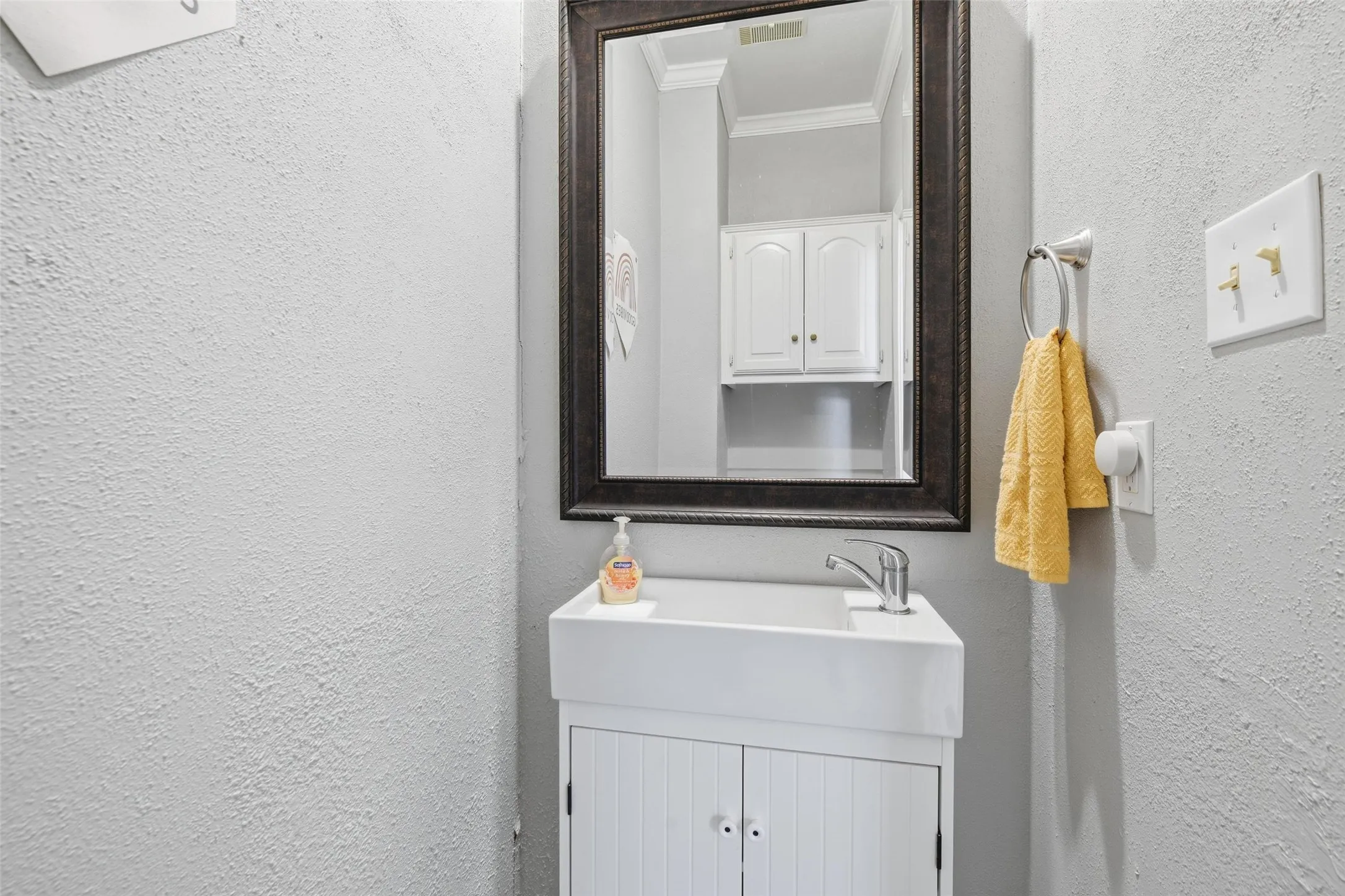 White vanity with beadboard door fronts, single basin sink, and chrome faucet