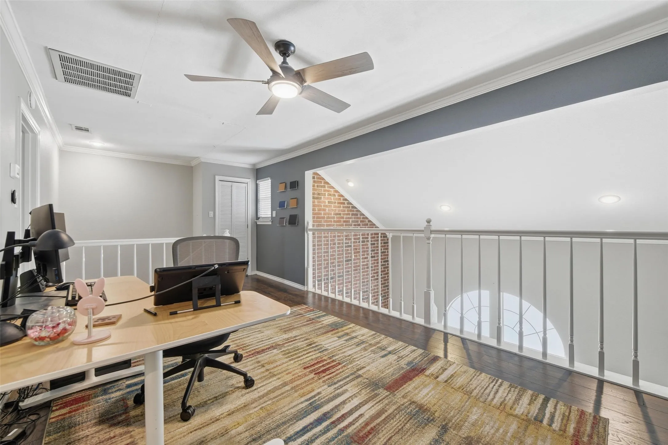 Loft space featuring dark wood-finish flooring, white railing, recessed lighting, and a ceiling fan with integrated light