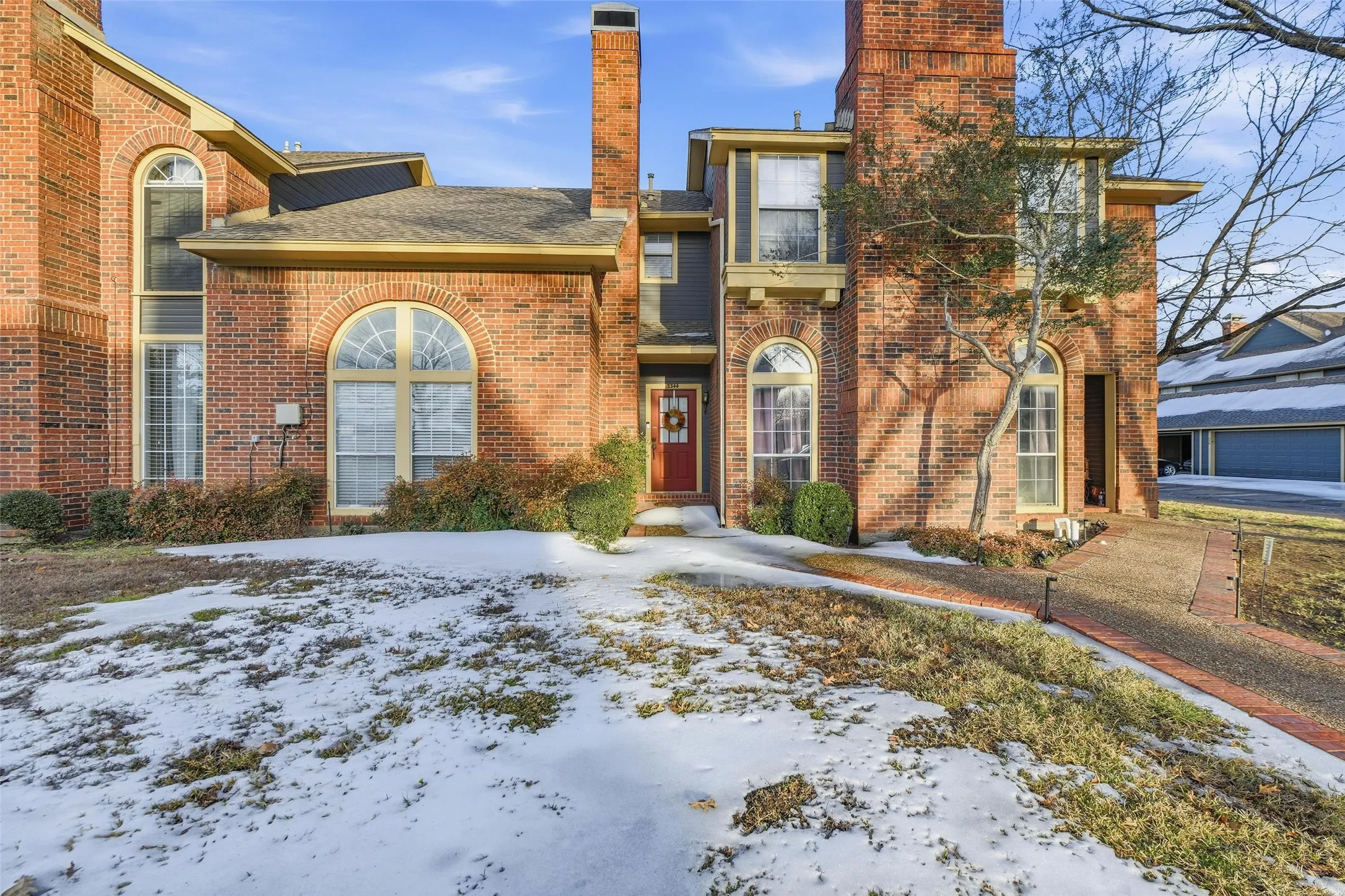 Brick exterior featuring arched windows, multiple chimneys, and an inviting red entry door