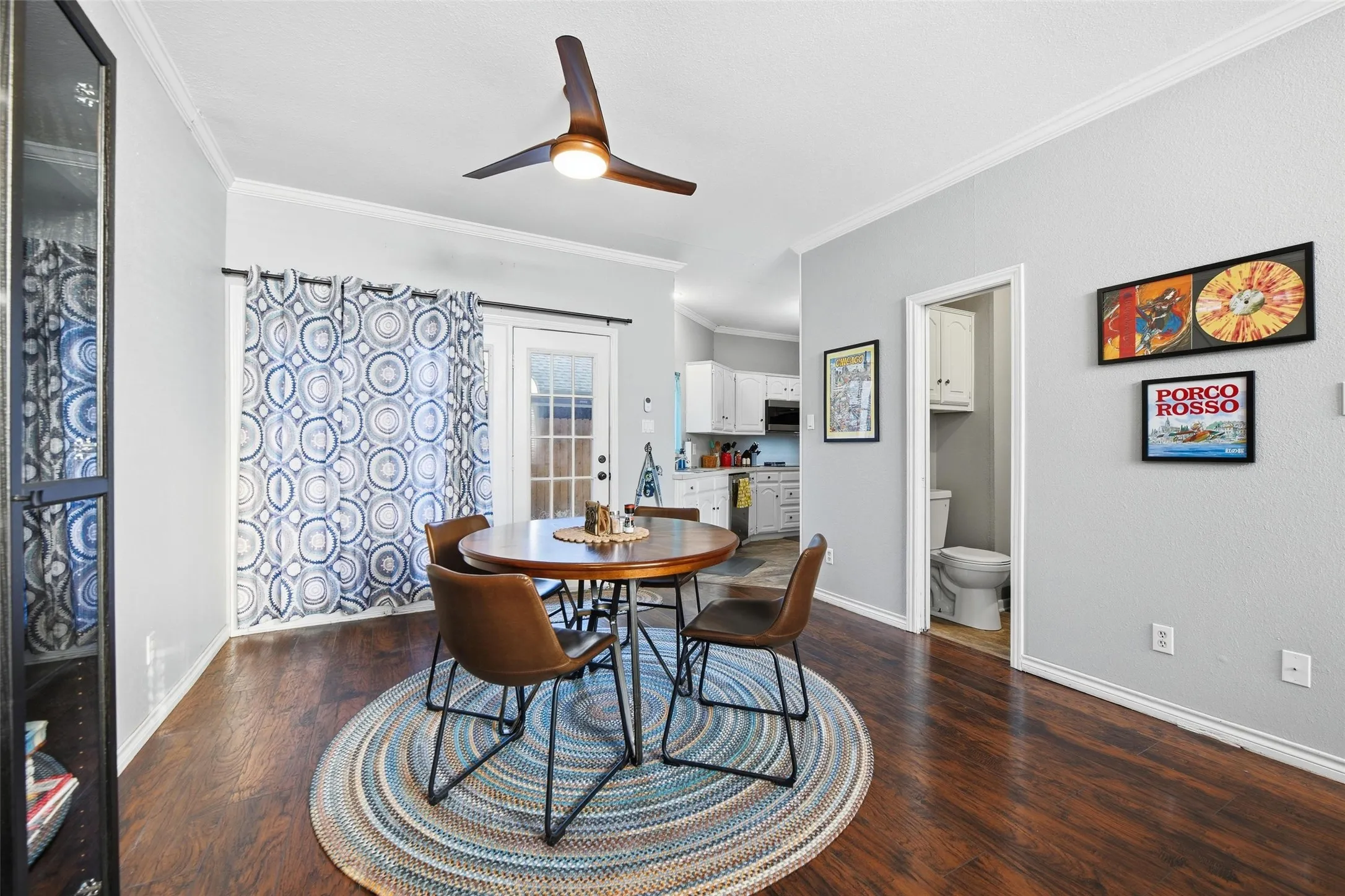 Wood-finish flooring throughout, a ceiling fan with integrated lighting, and crown molding