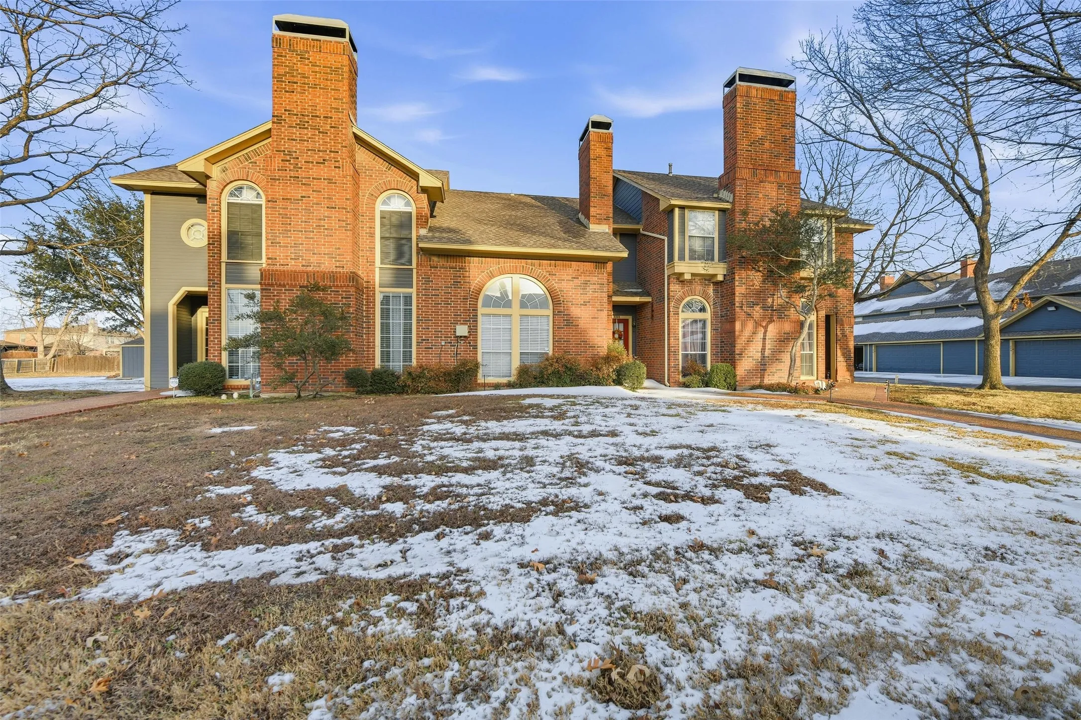 Brick exterior with multiple prominent chimneys, arched windows, and a gabled roofline