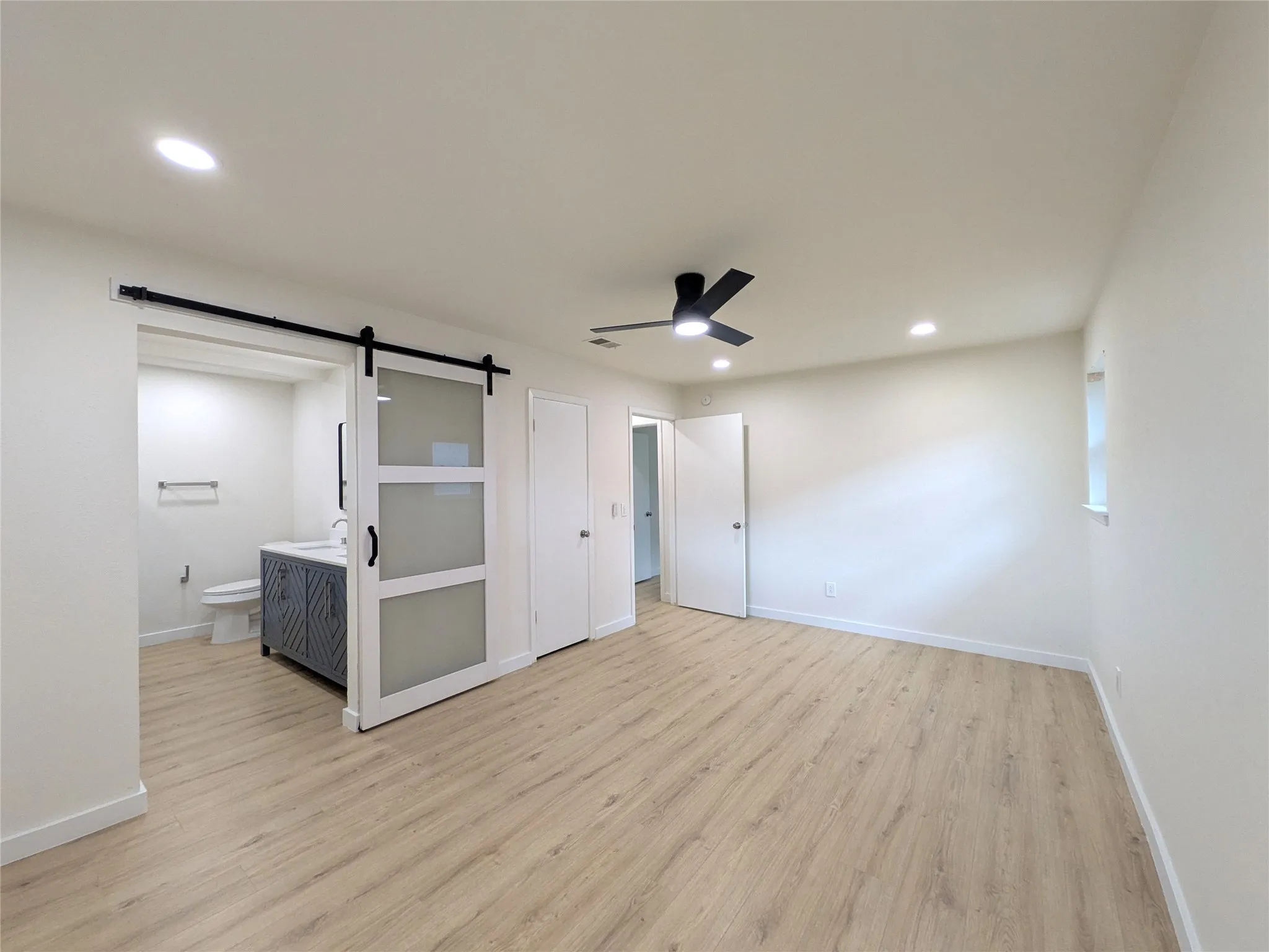 Spacious room featuring wood-finish flooring, recessed lighting, and a contemporary ceiling fan