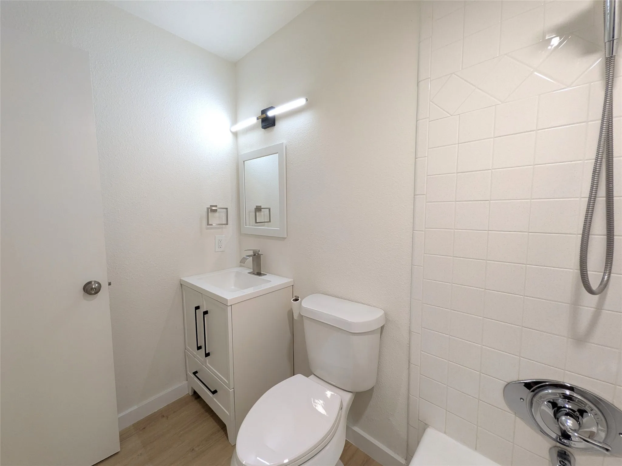 Contemporary bathroom featuring a white vanity with black hardware, a rectangular sink, and a chrome faucet