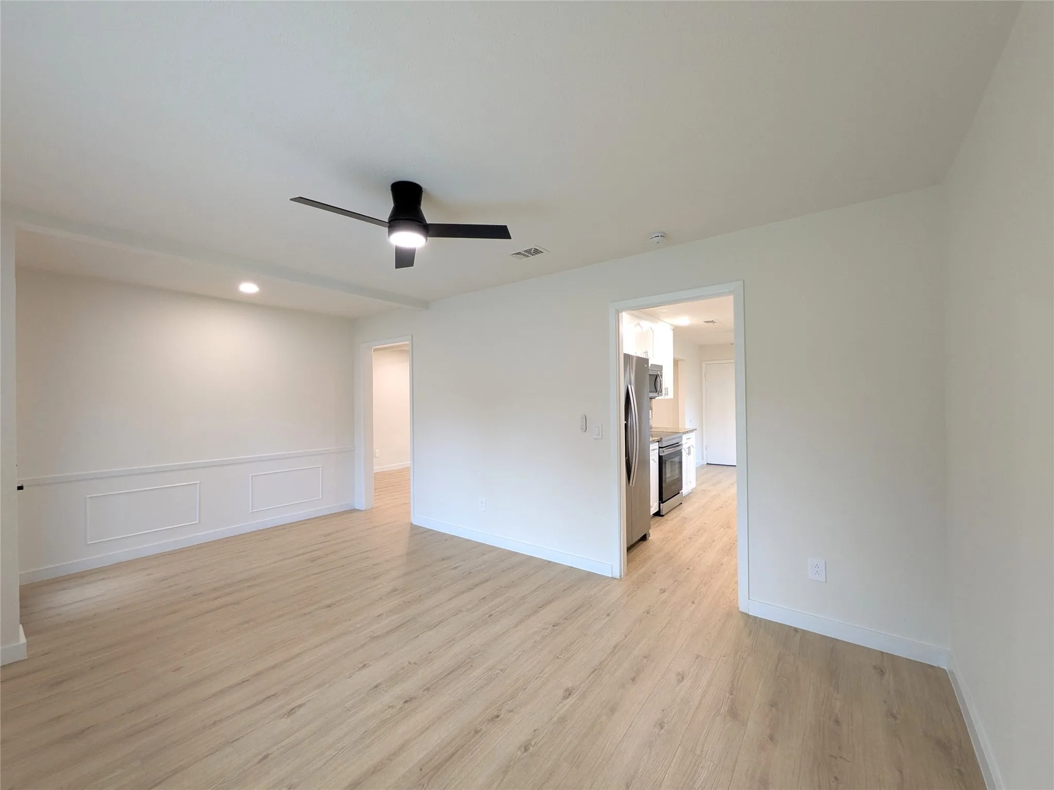 Open-concept living area with wood-finish flooring, white walls, and a contemporary ceiling fan