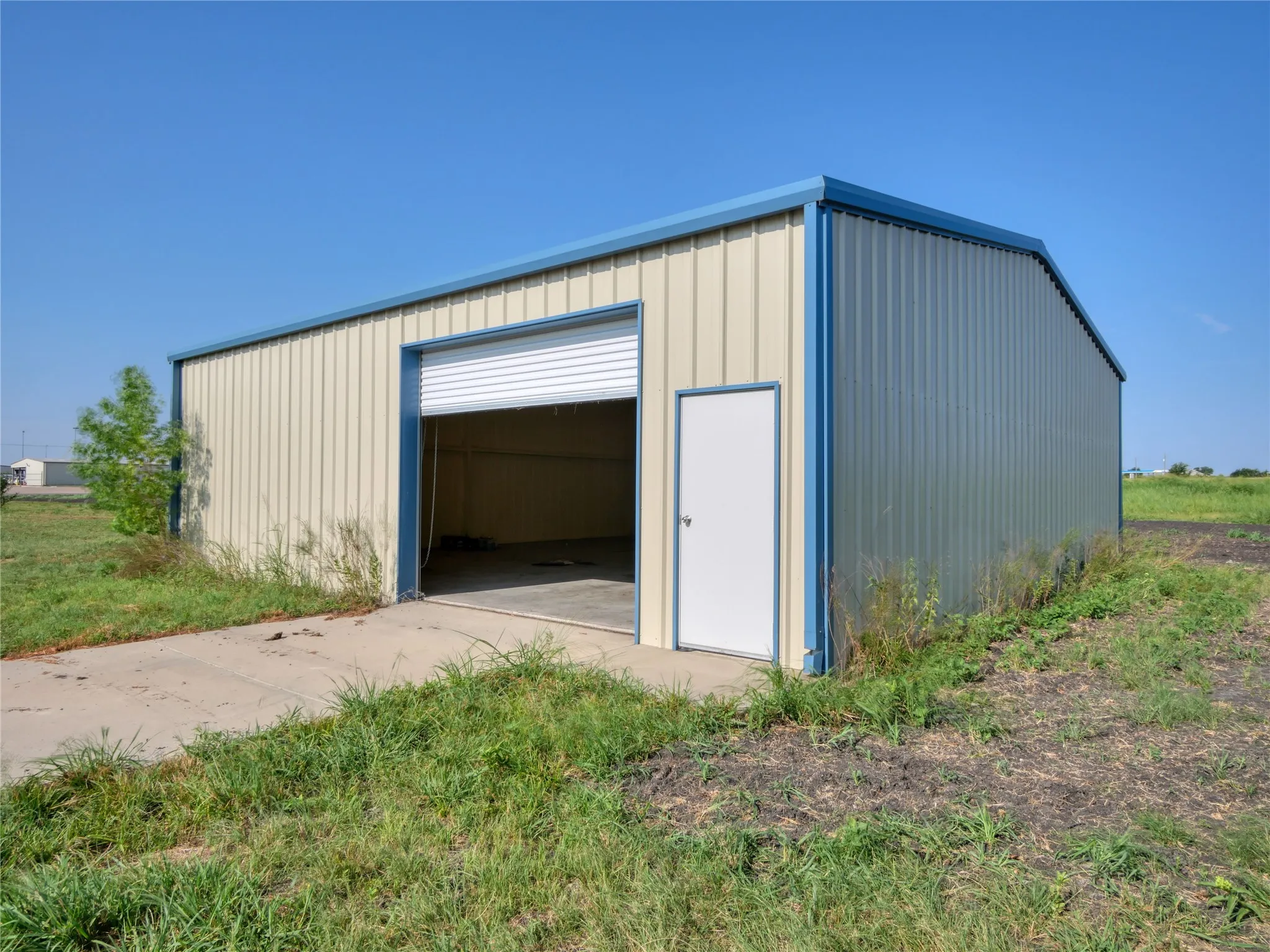 Metal utility building with a roll-up door, pedestrian entry door, and concrete pad