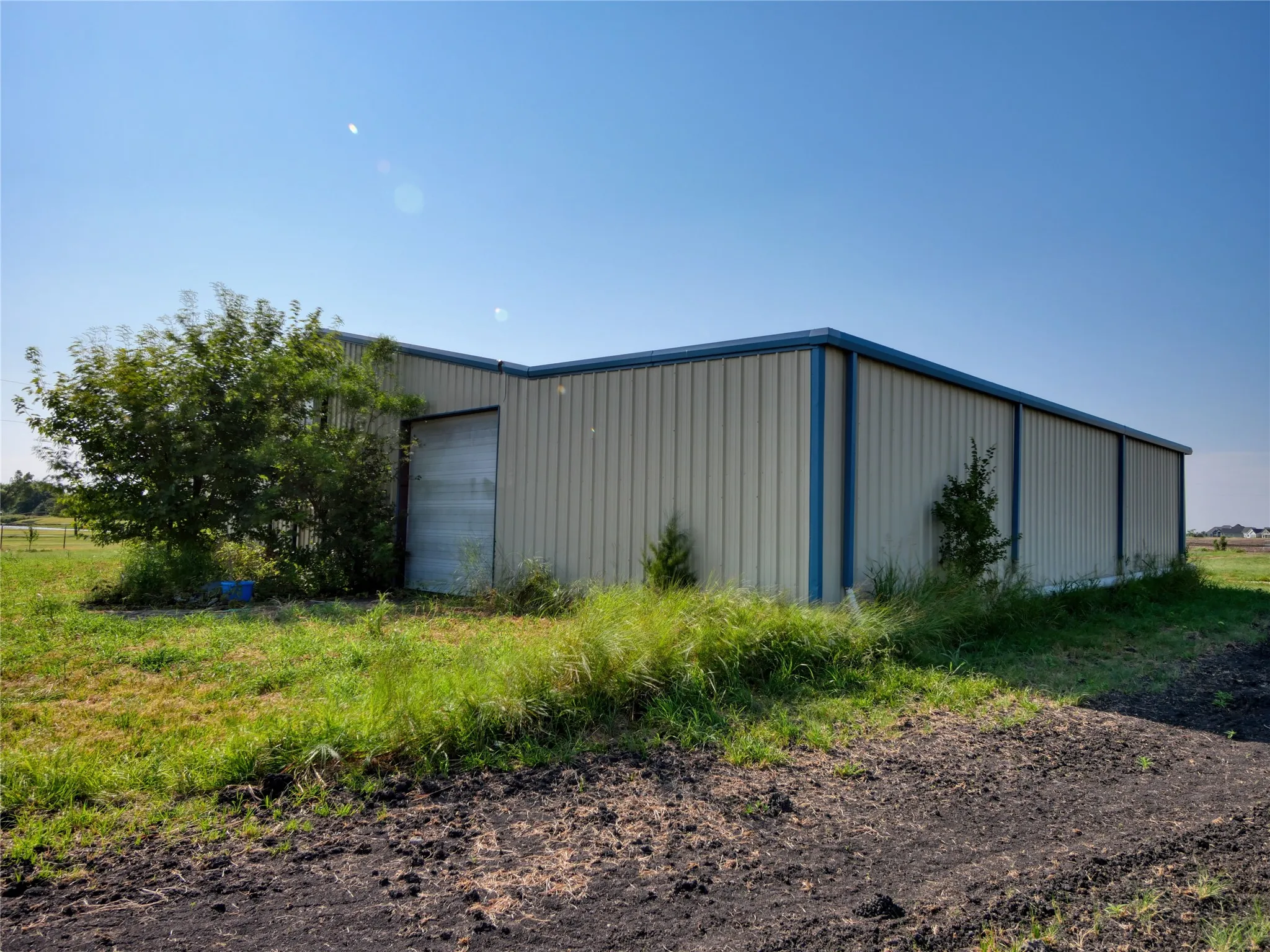Metal-sided outbuilding with blue trim, featuring a large roll-up door