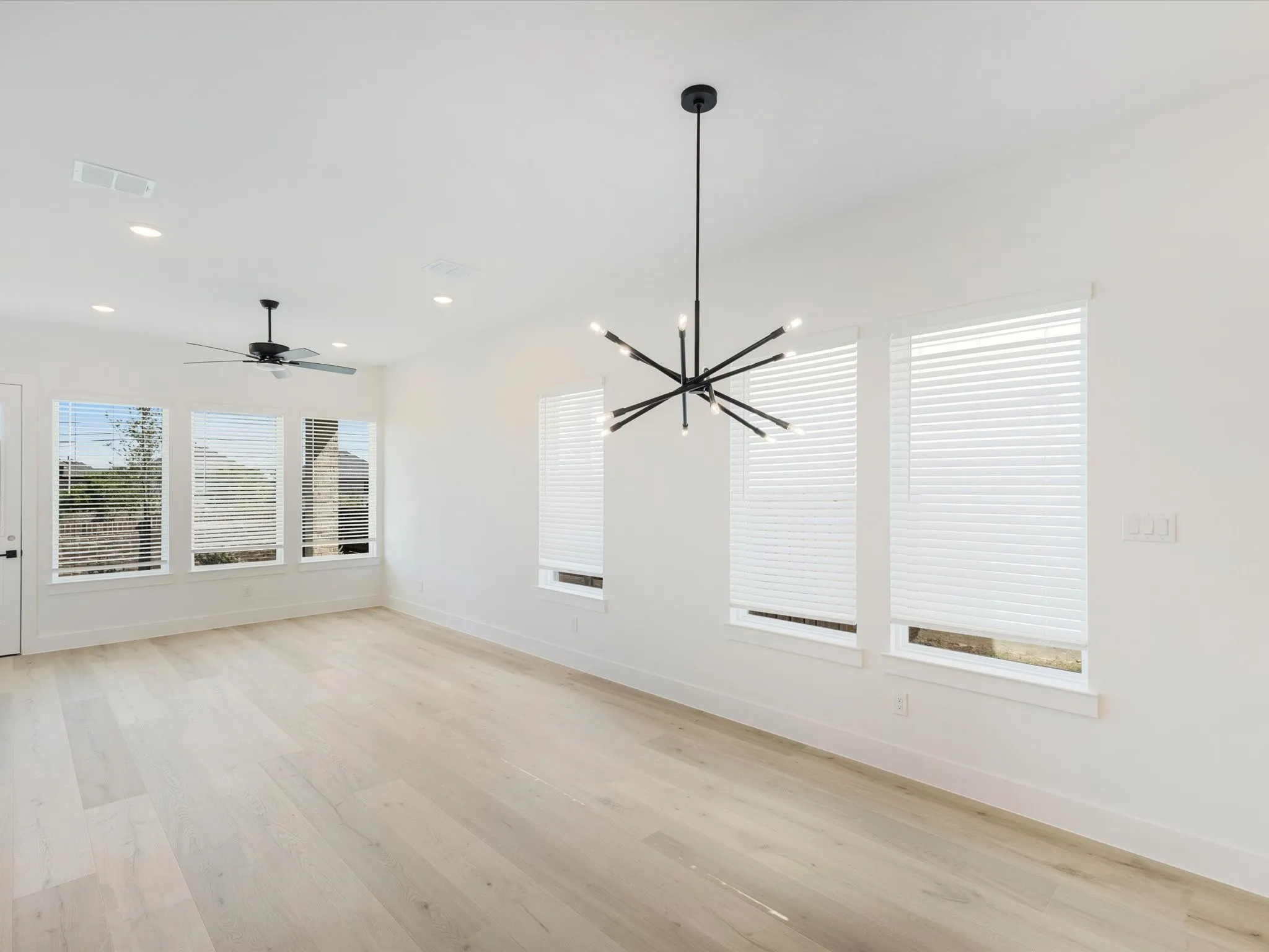 Unfurnished dining area featuring light wood-style flooring, a chandelier, ceiling fan, and recessed lighting