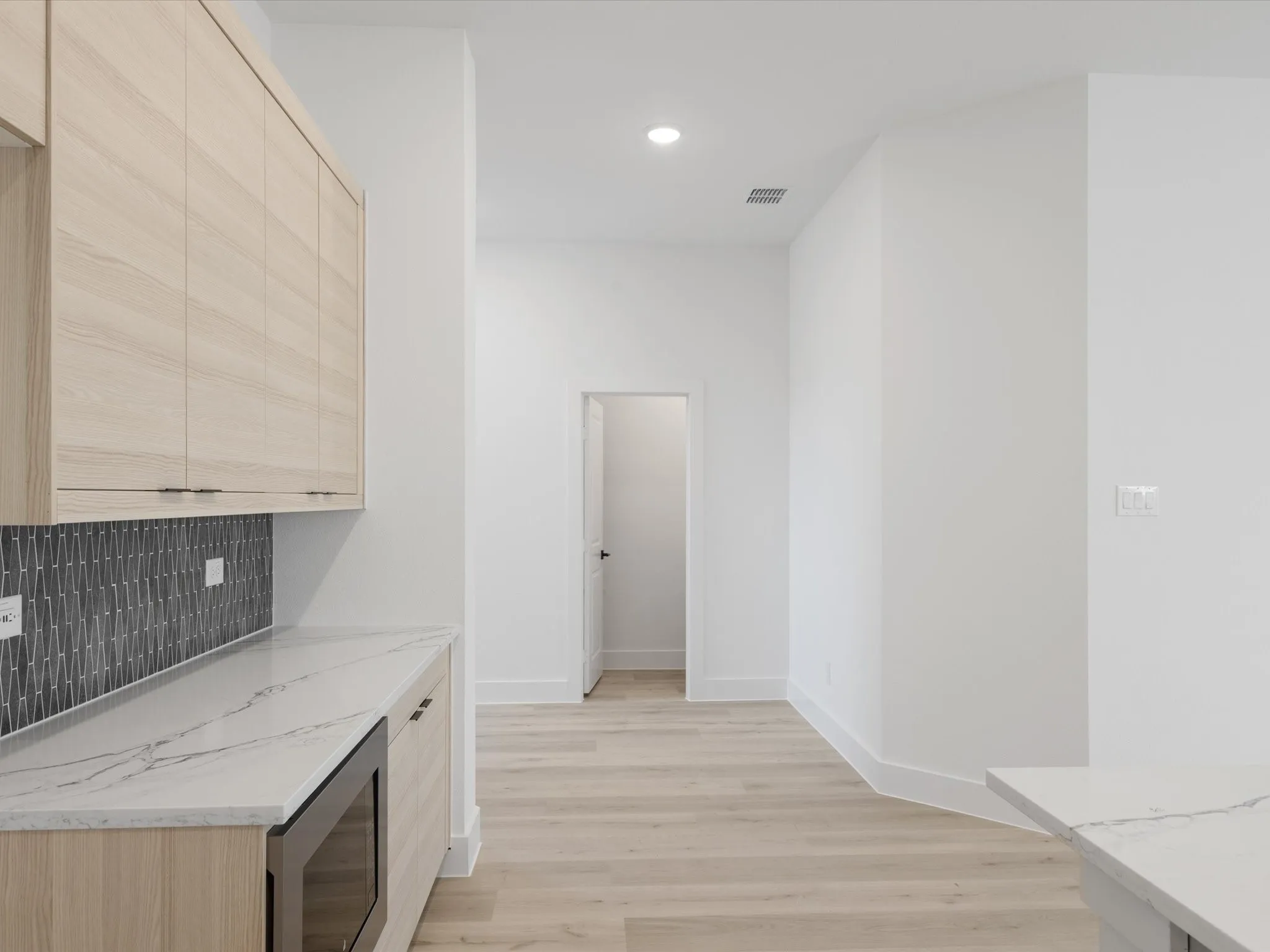 Bar featuring light brown cabinetry, light stone countertops, light wood-style flooring, tasteful backsplash, and recessed lighting
