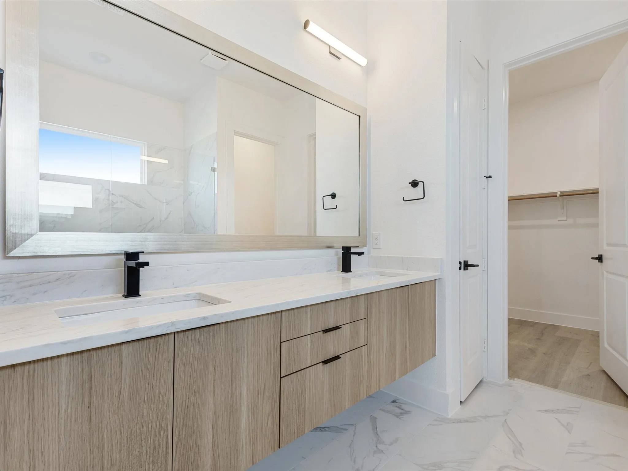 Primary Bathroom with light marble finish flooring, a spacious closet, and a marble finish shower