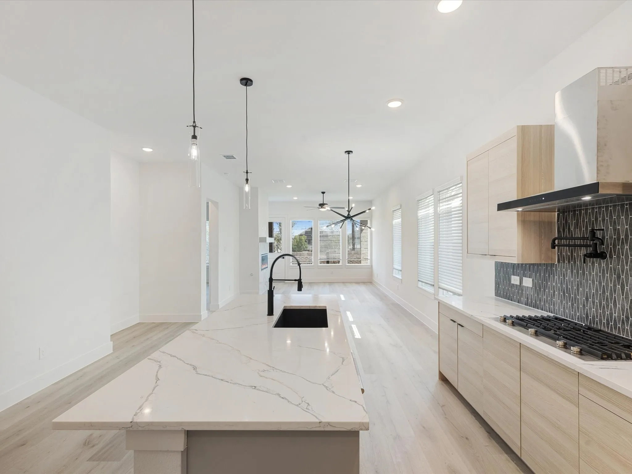 Kitchen featuring light brown cabinets, modern cabinets, light stone countertops, and recessed lighting