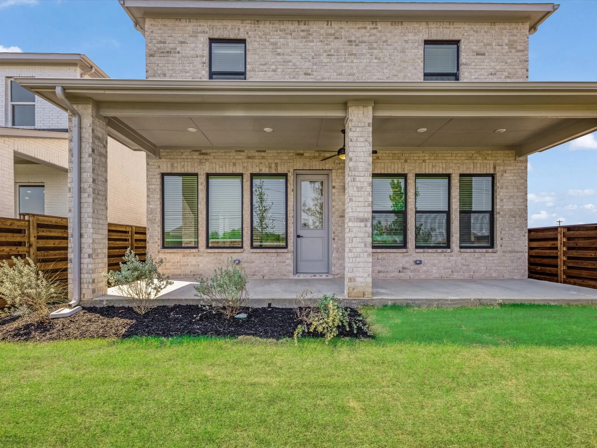 Rear view of house featuring brick siding, ceiling fan, and a patio area