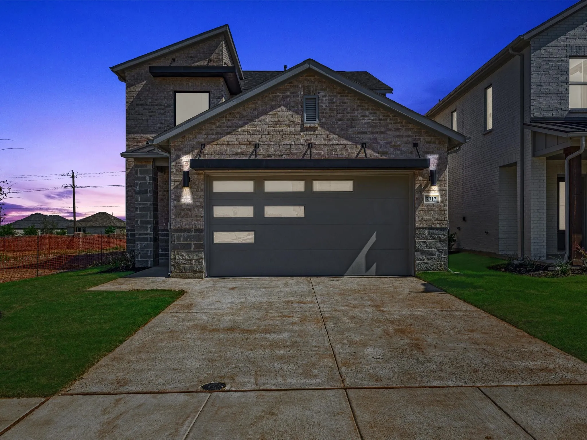 View of front of property featuring stone siding, a garage, a front lawn, and driveway