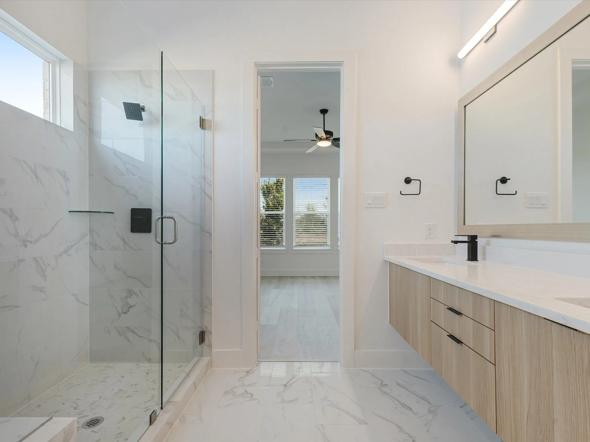 Primary Bathroom with healthy amount of natural light, a marble finish shower, light marble finish flooring