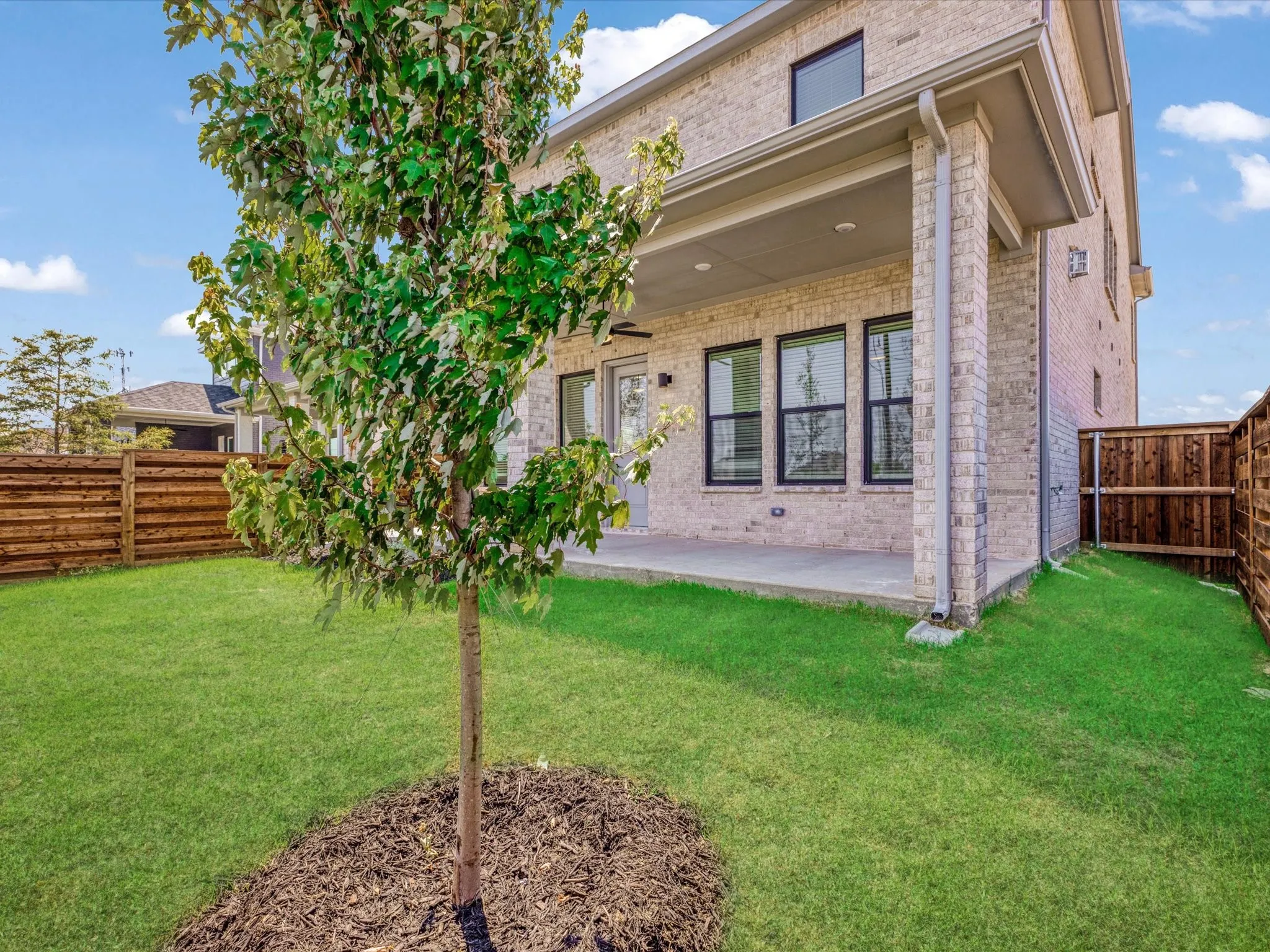 Rear view of house featuring a fenced backyard, brick siding, a patio area, and ceiling fan